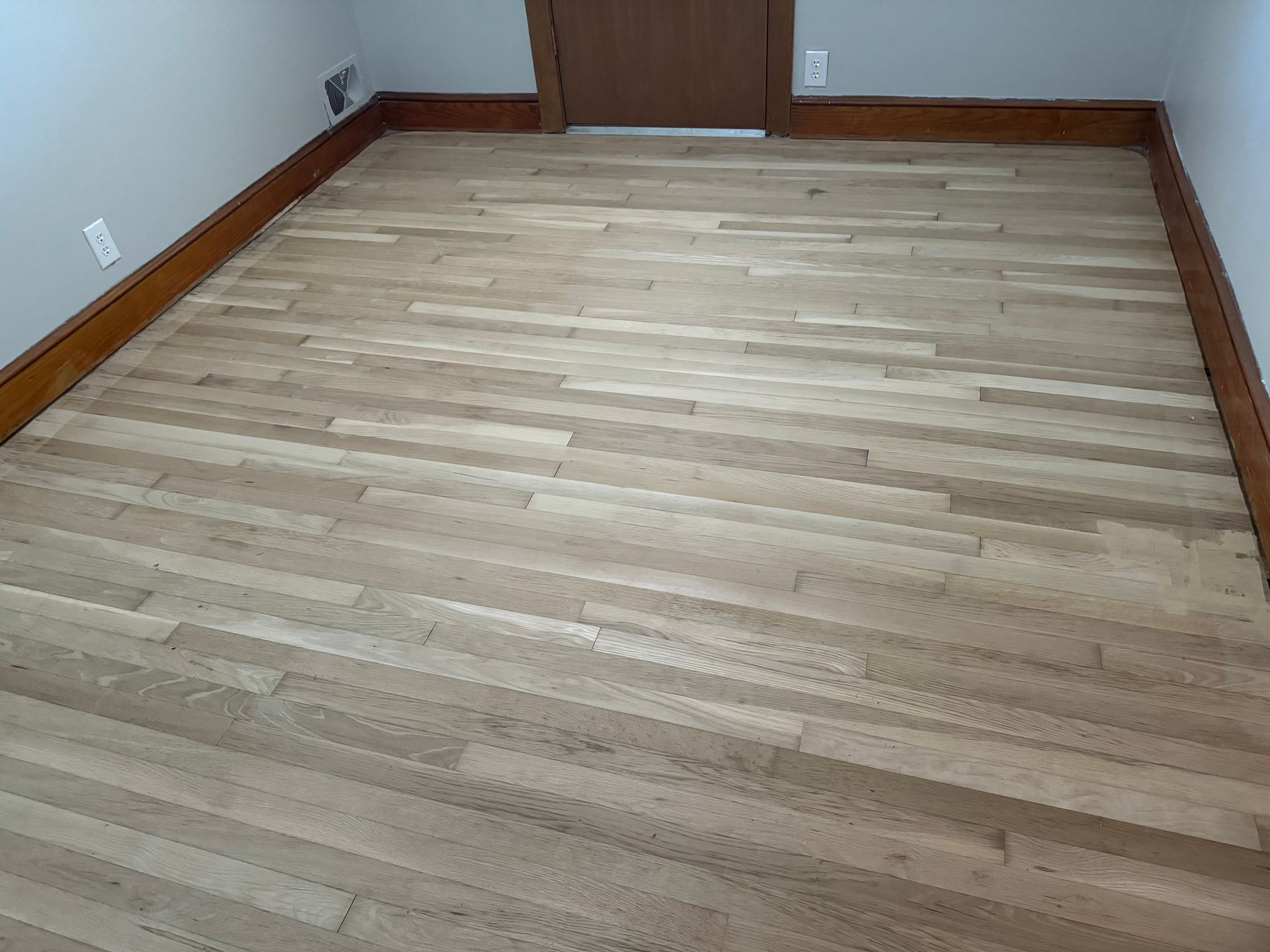 A room with a wooden floor and a door.