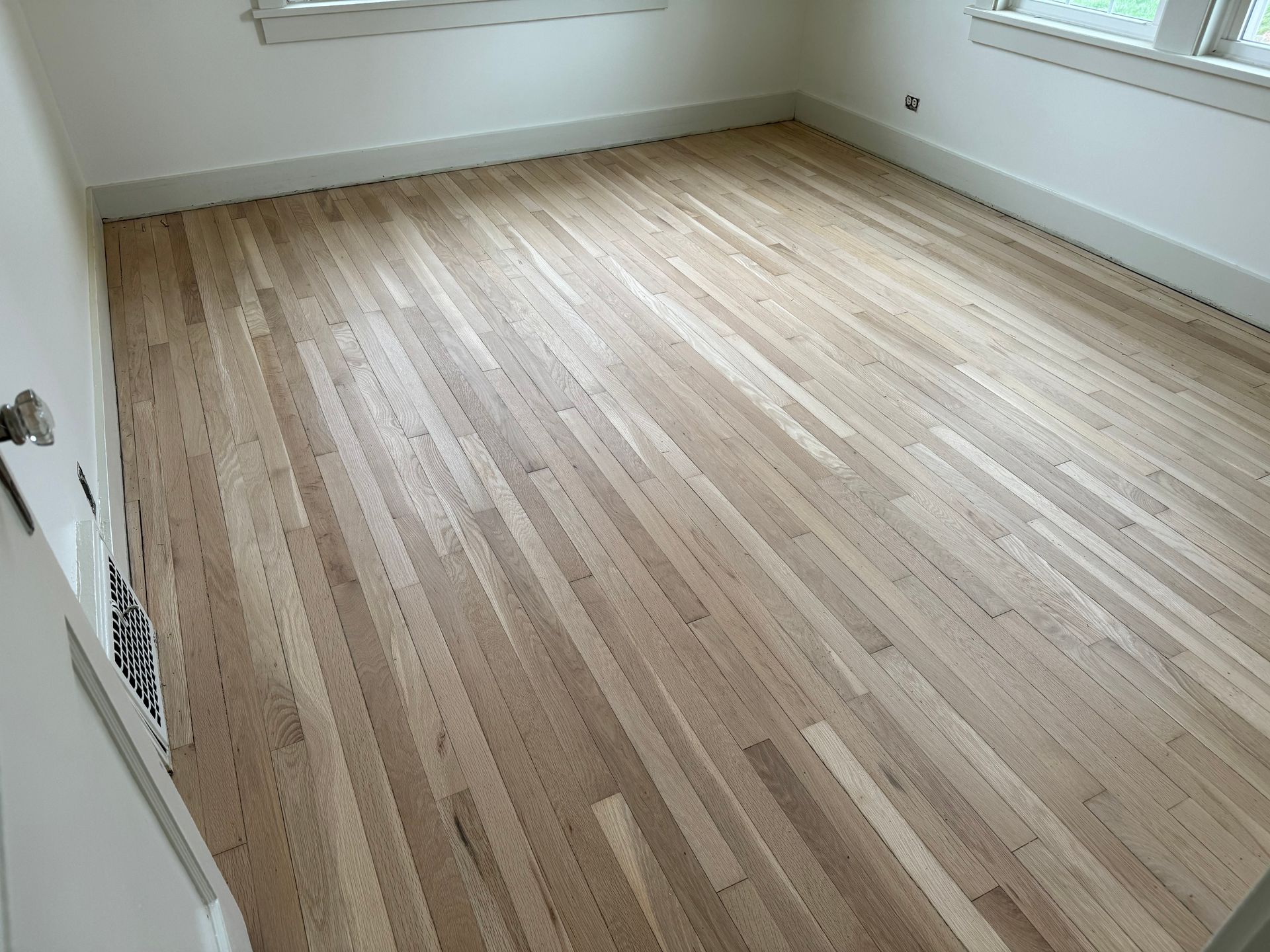 A bedroom with hardwood floors and white walls.