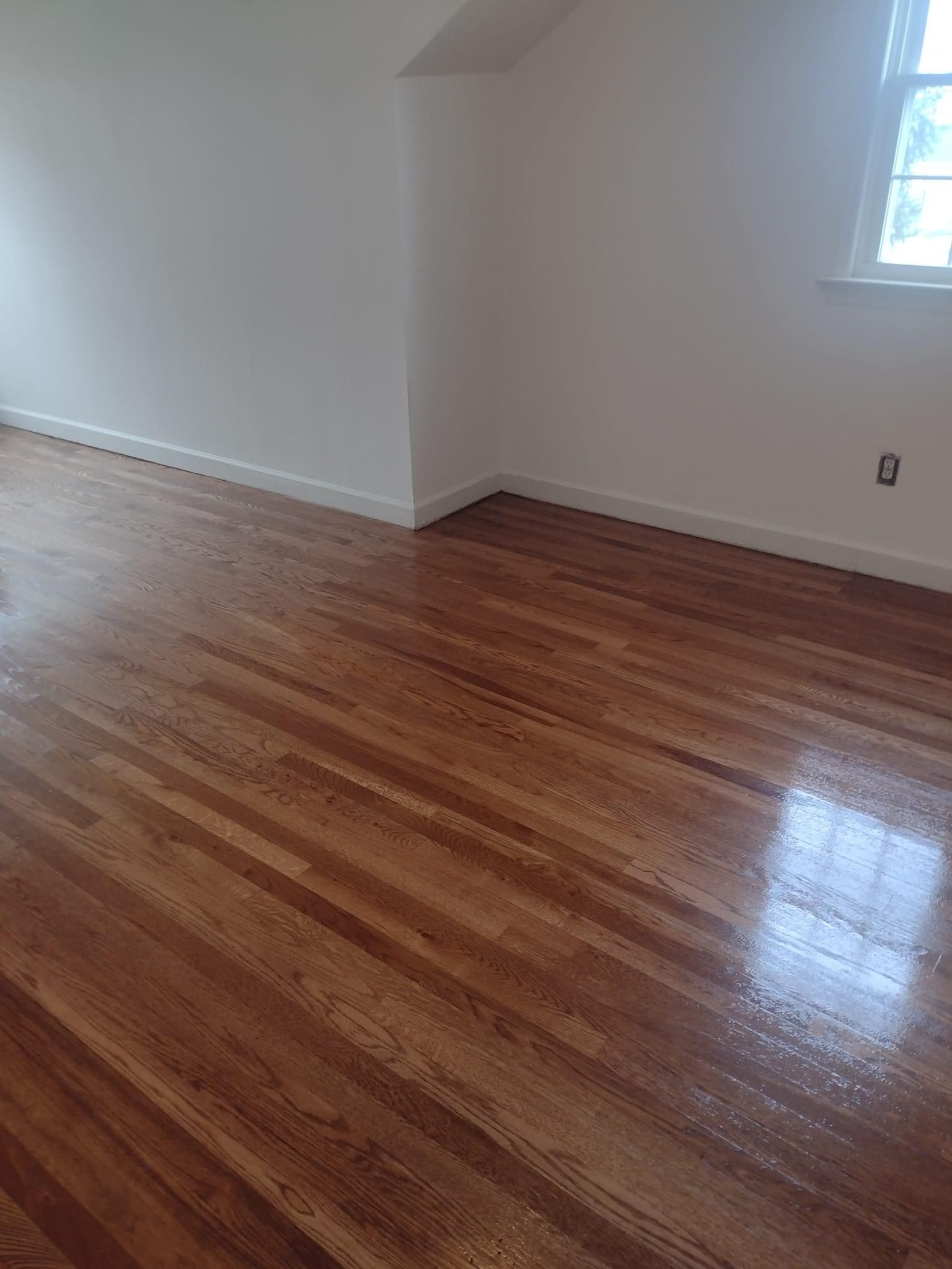 An empty room with hardwood floors and white walls.