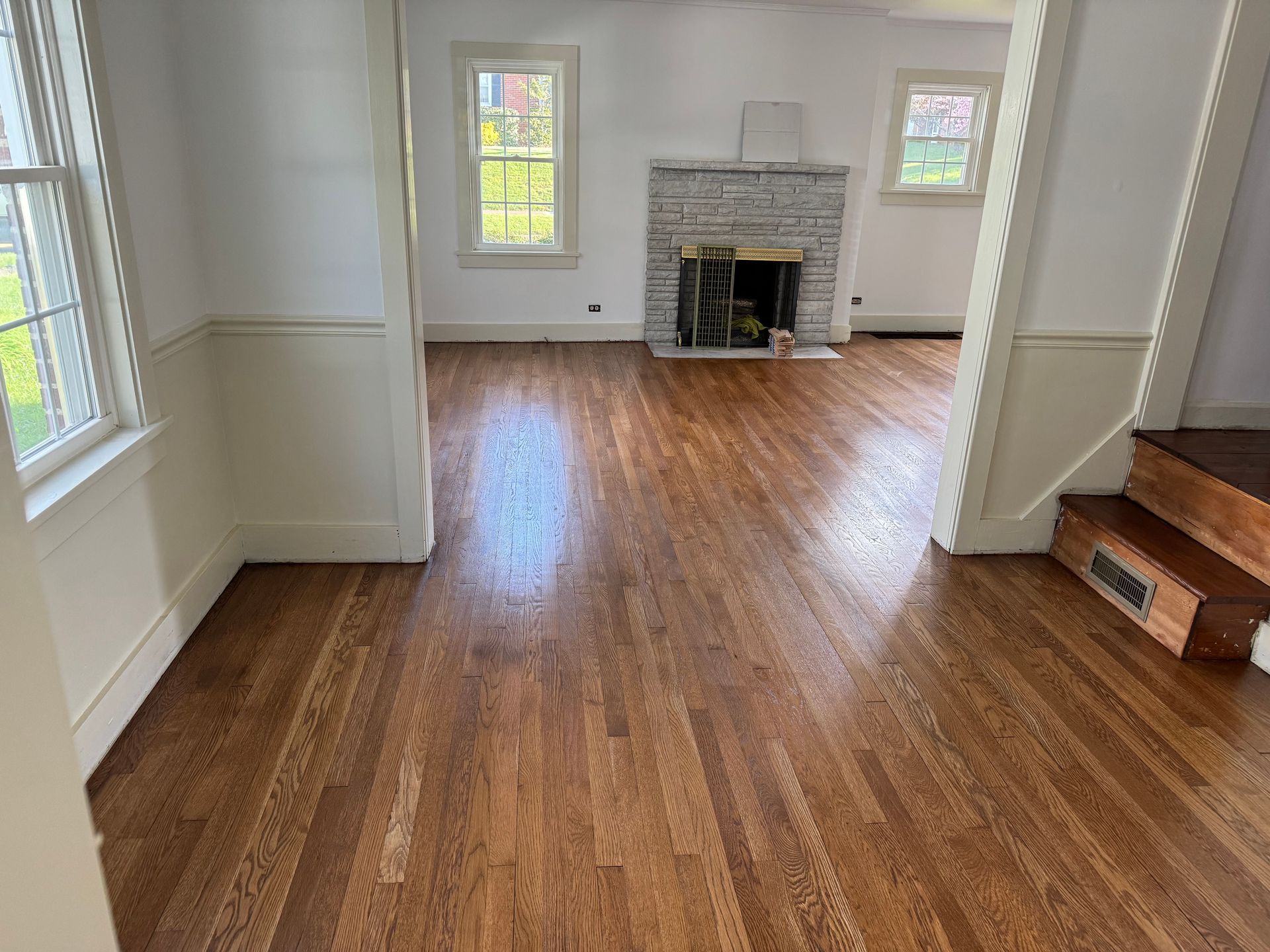 An empty living room with hardwood floors and a fireplace.