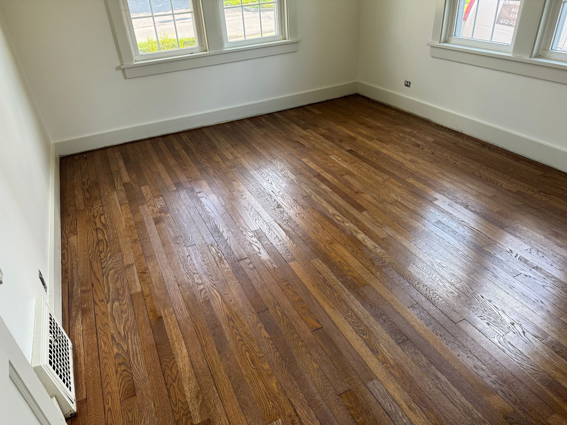 An empty room with hardwood floors and white walls.