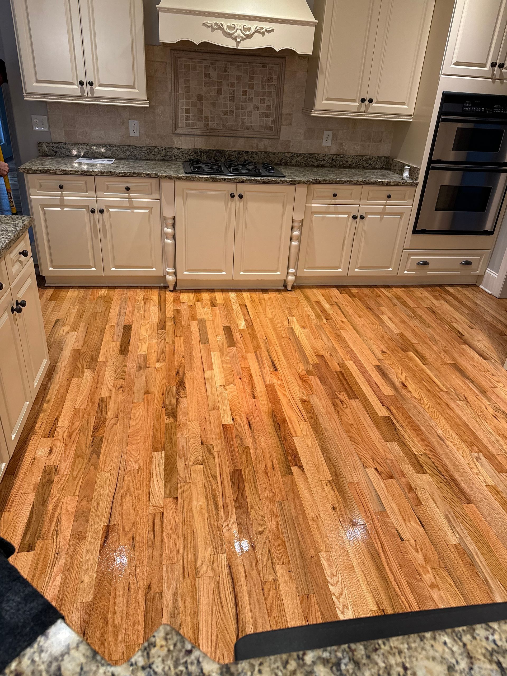 A kitchen with hardwood floors and white cabinets.