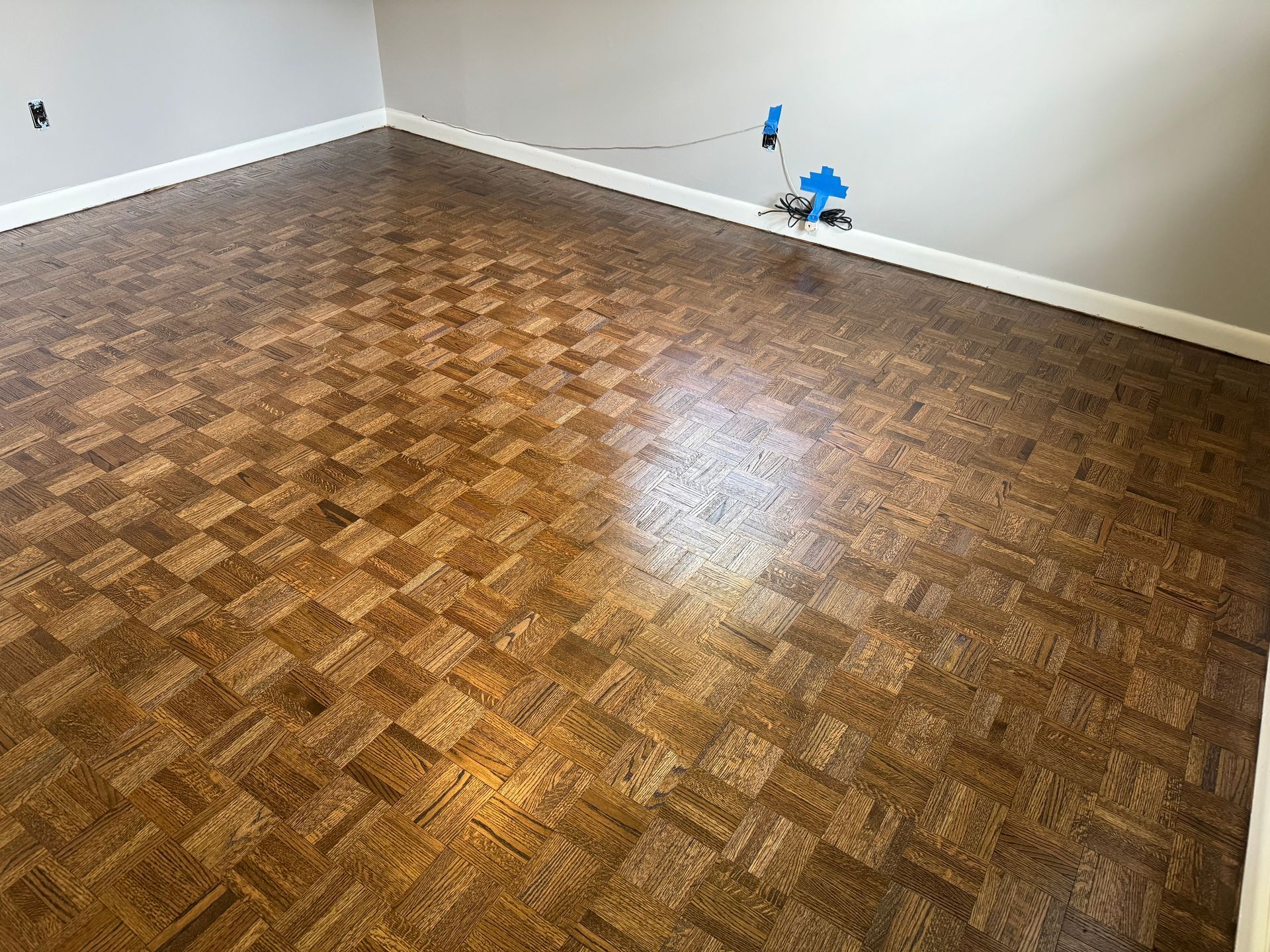 A room with a wooden floor and a gray wall.