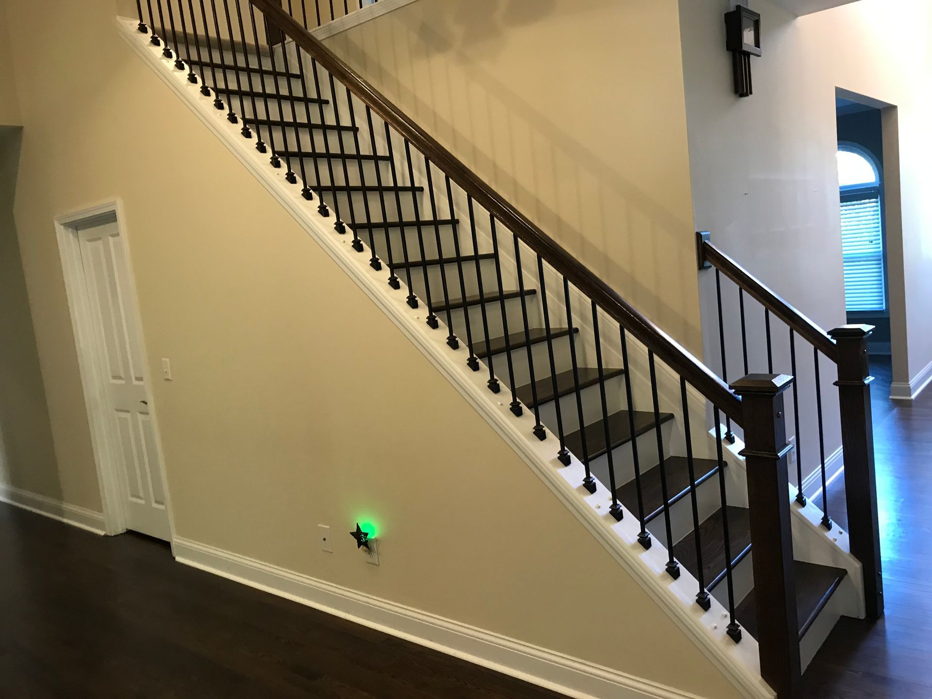A staircase in a house with a green light on the wall.