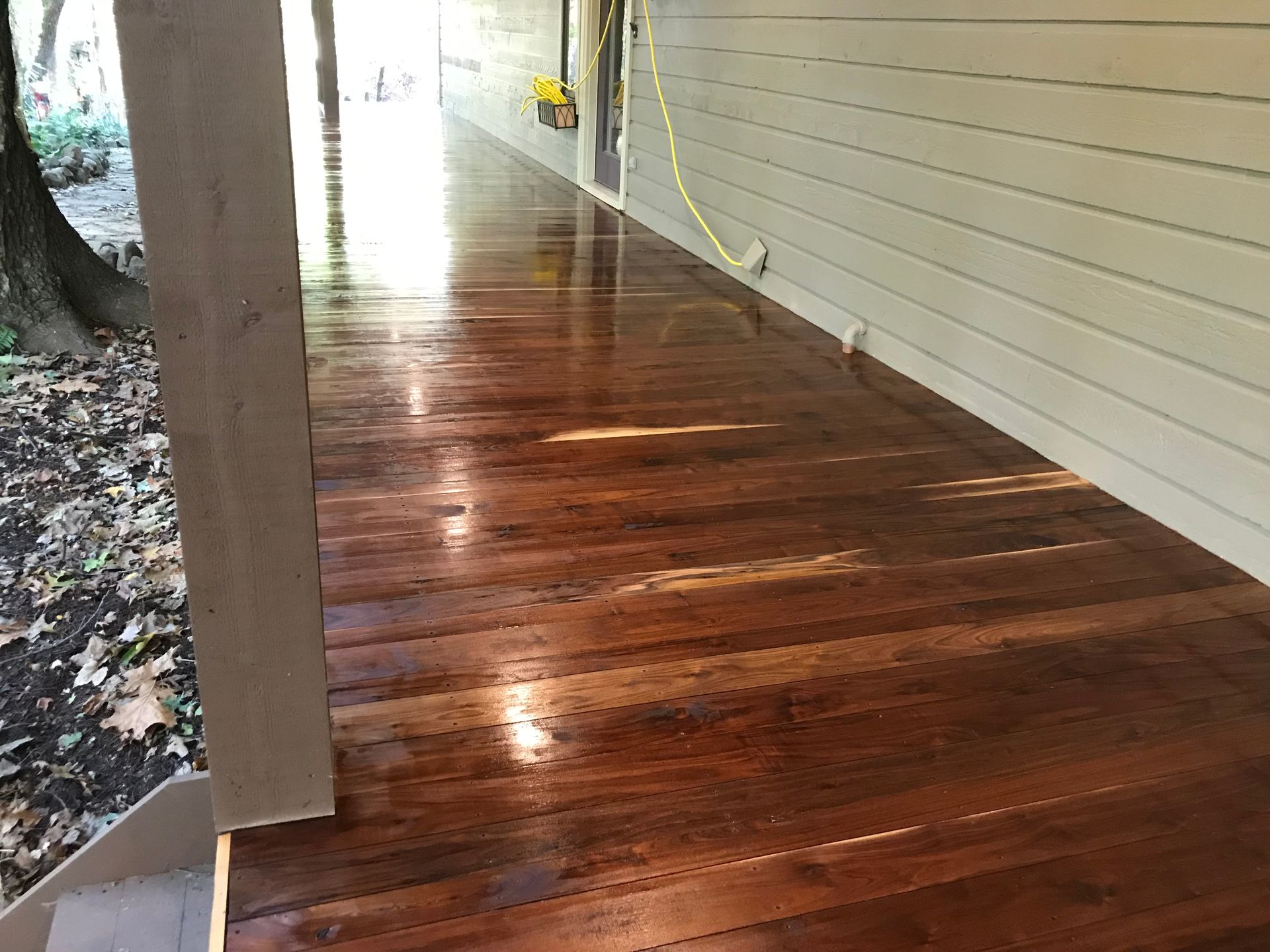 A wooden porch with a white house in the background.