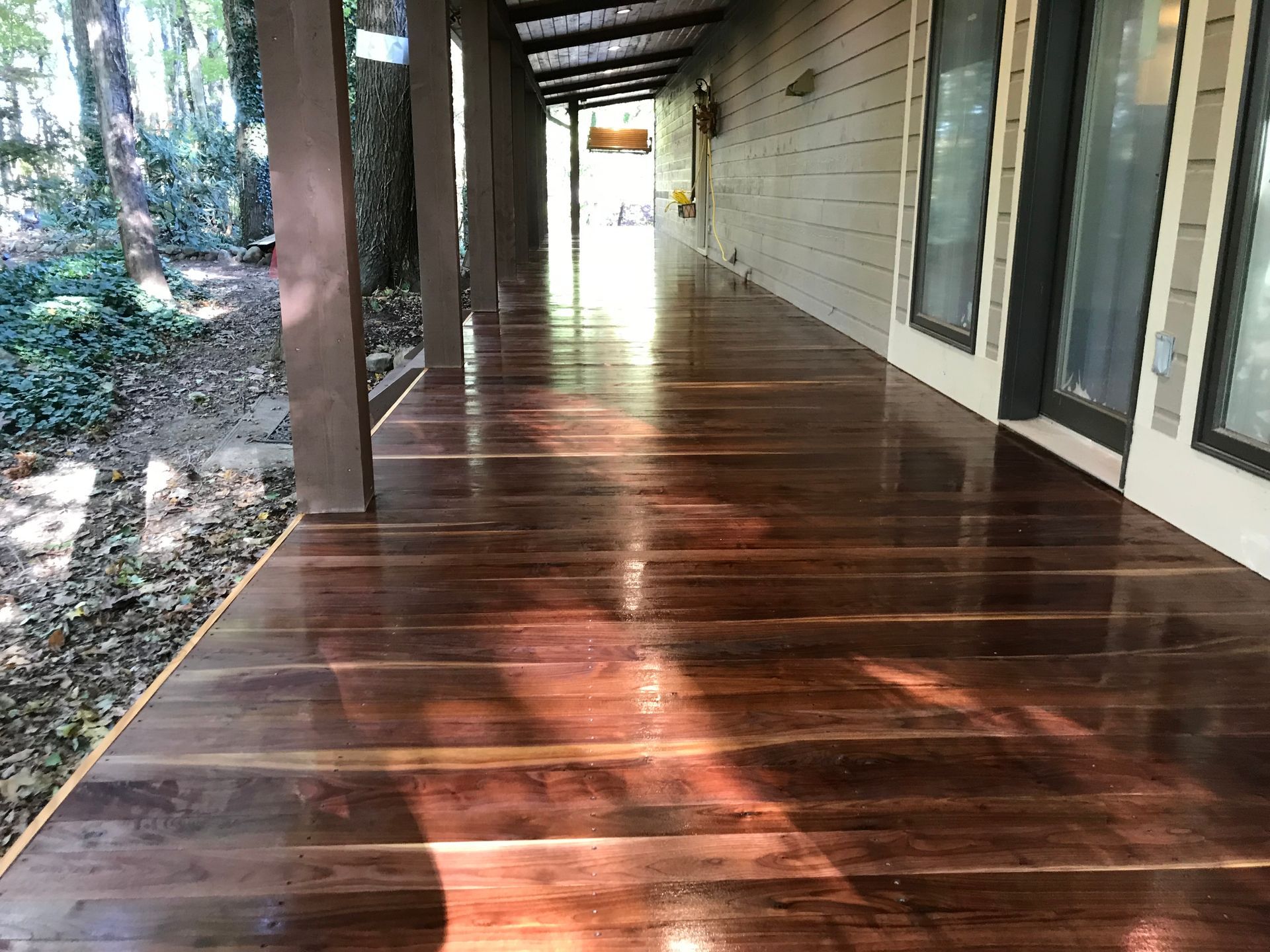 A long wooden walkway leading to a house with a lot of windows.