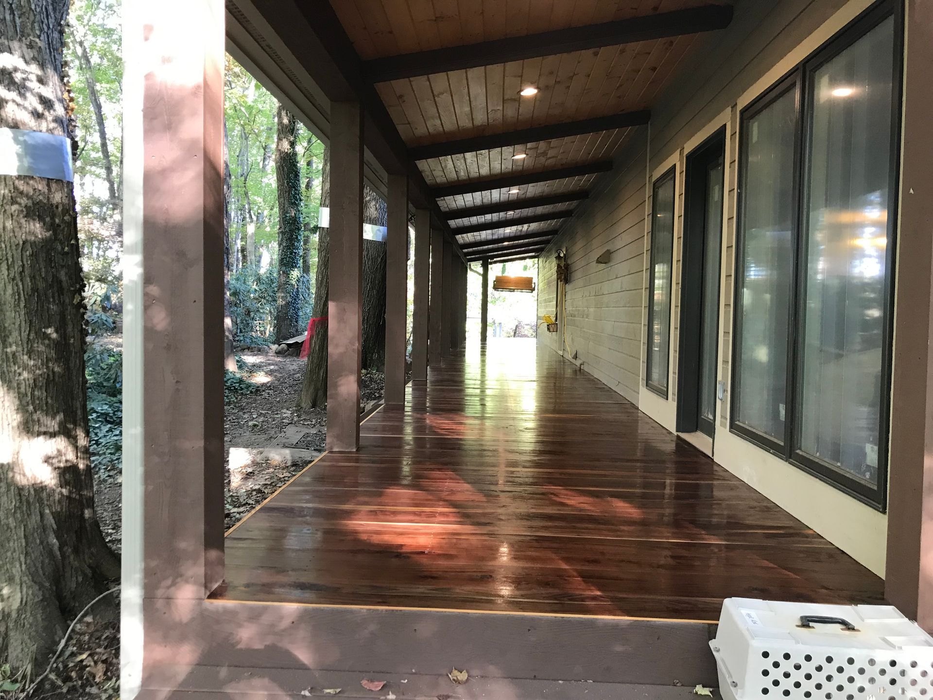 A dog crate is sitting on the side of a wooden porch.