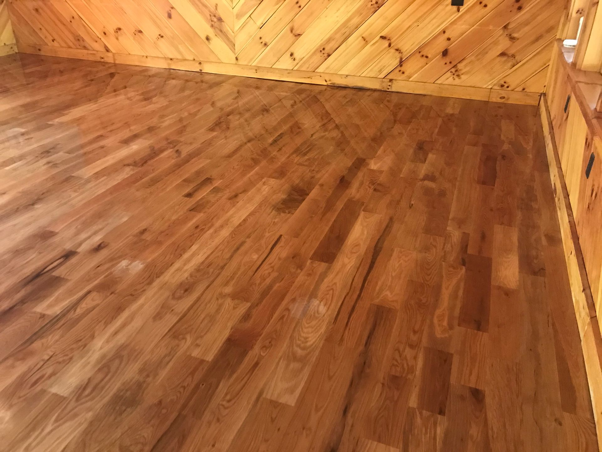 A room with hardwood floors and wood paneling on the walls.
