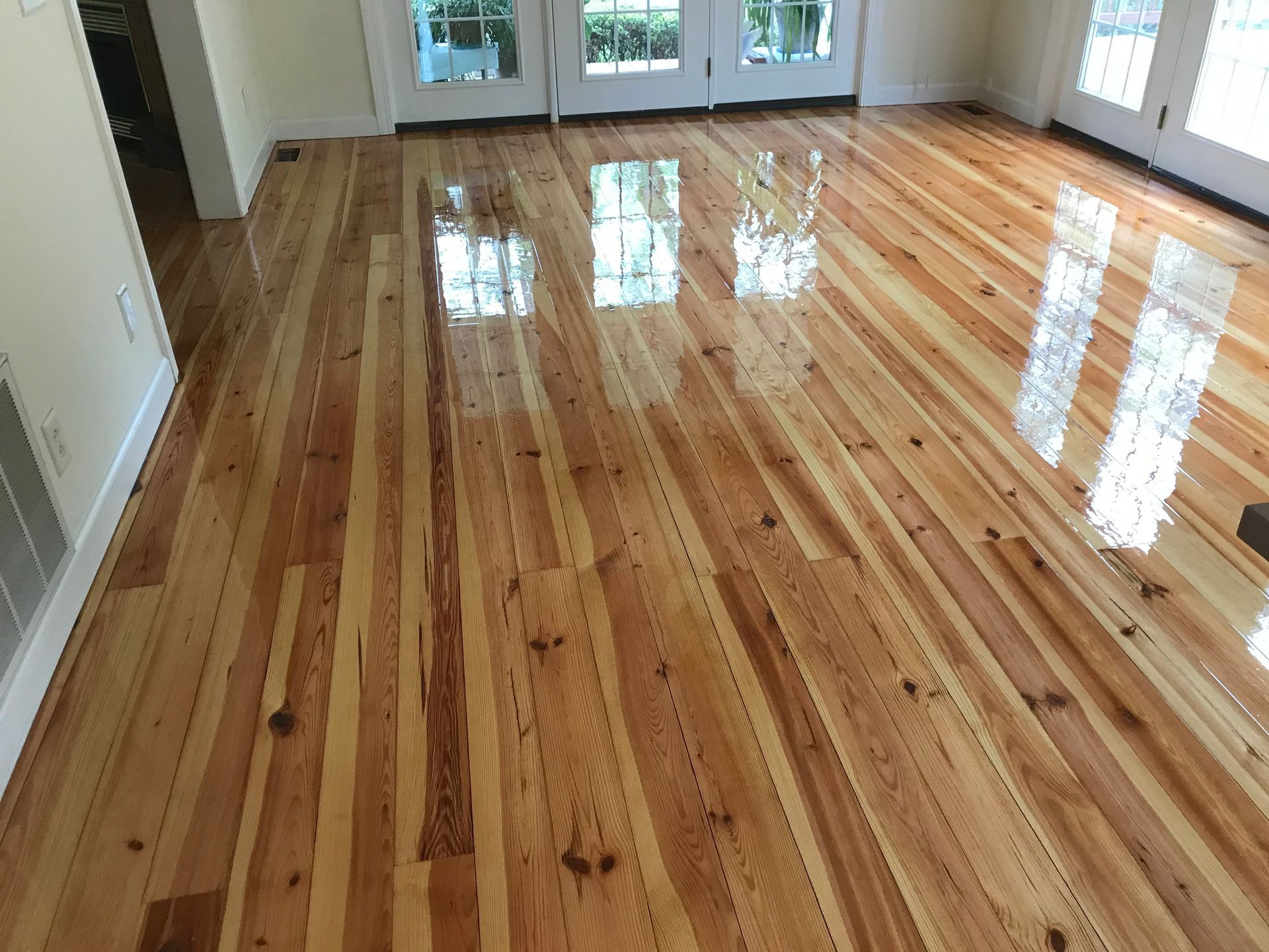 A living room with a wooden floor and sliding glass doors.