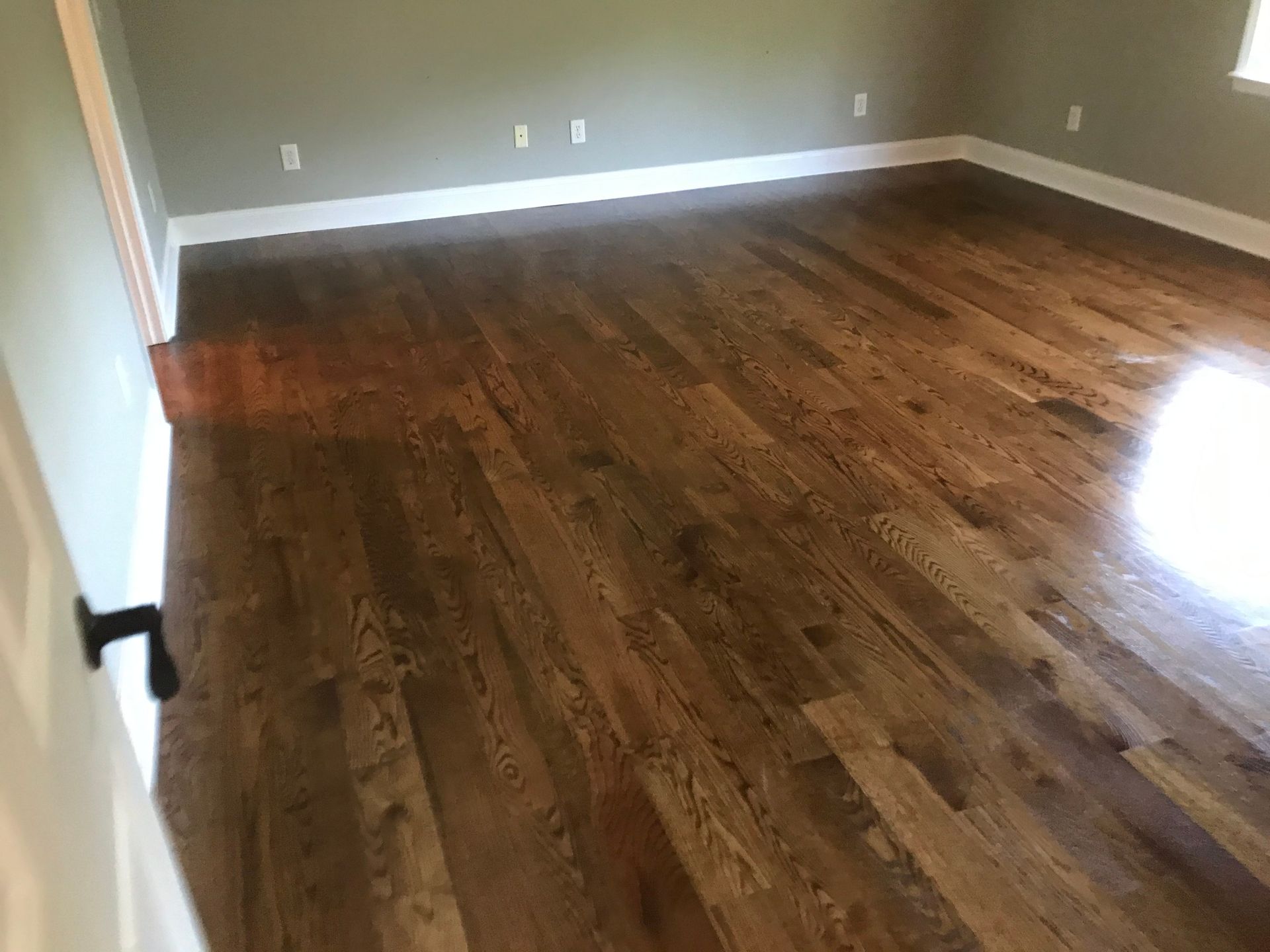 A large empty room with hardwood floors and a window.