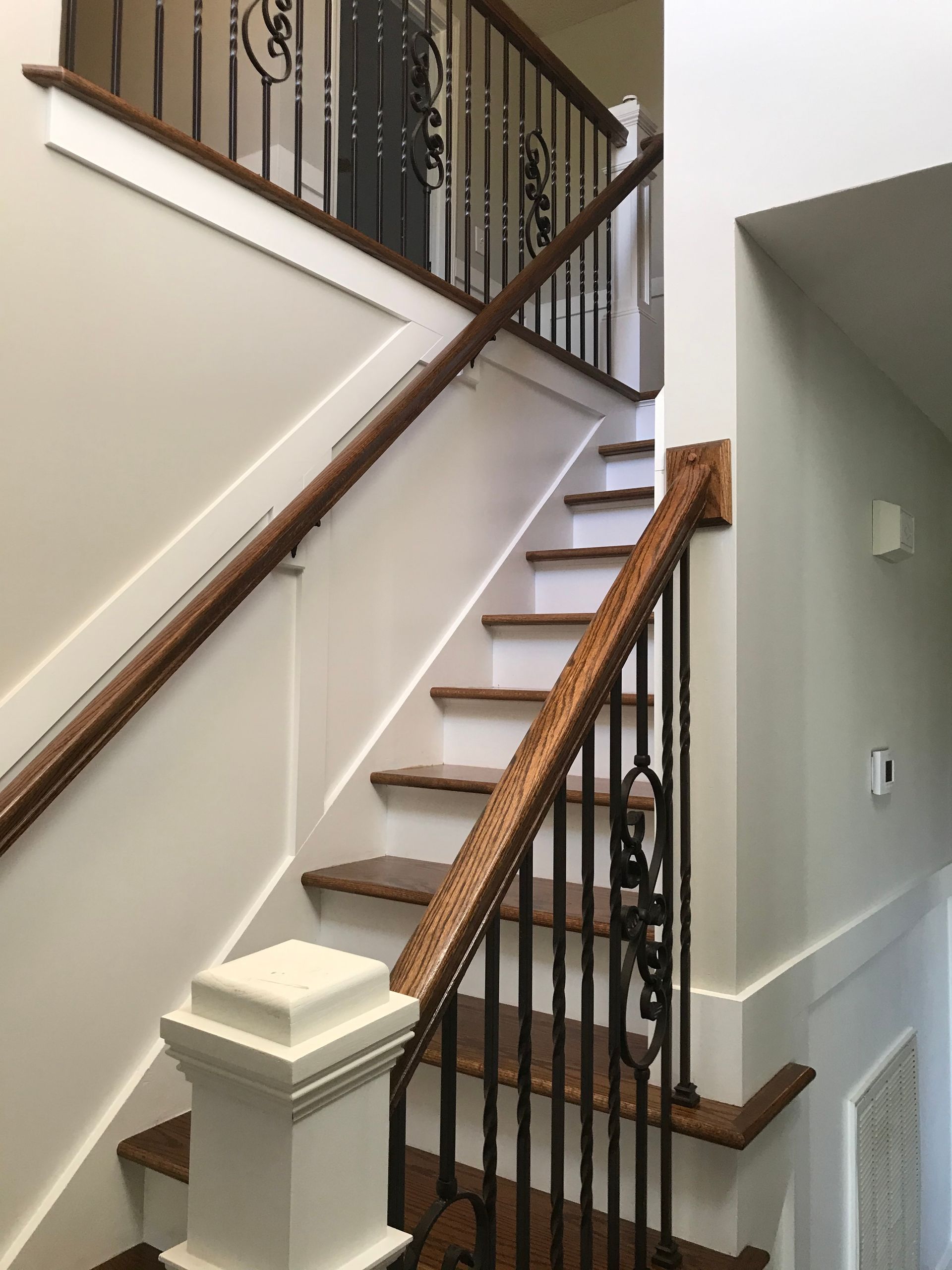 A staircase with a wrought iron railing and wooden handrails