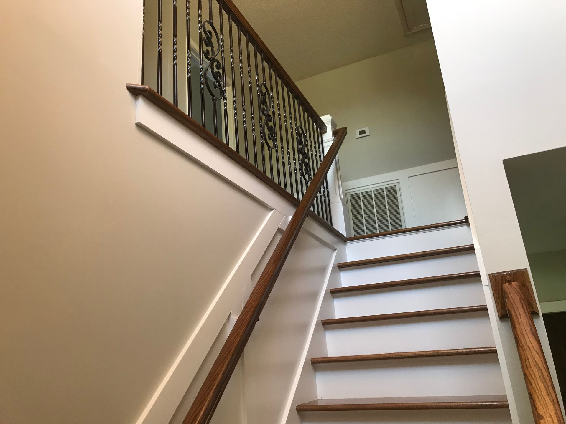A wooden staircase with a wrought iron railing in a house.