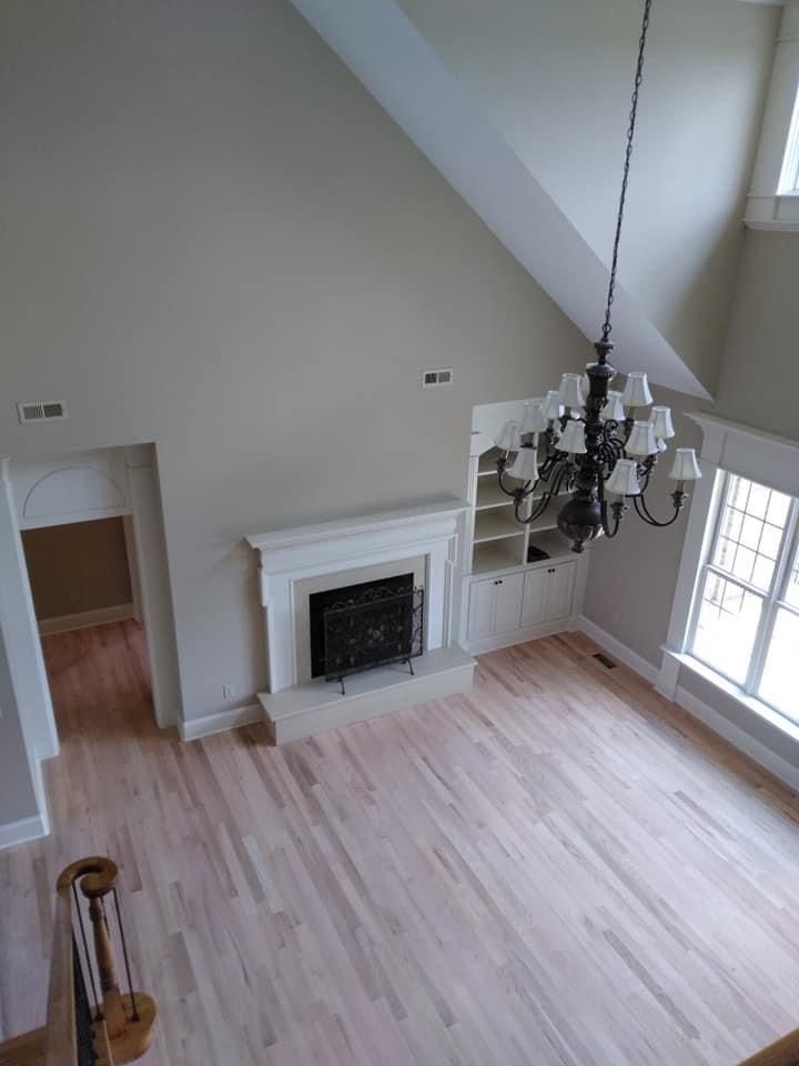 A living room with hardwood floors , a fireplace and a chandelier.