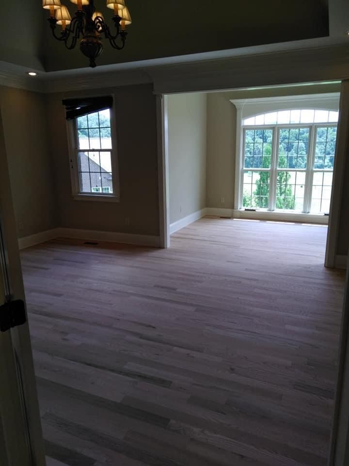 An empty room with hardwood floors and a chandelier