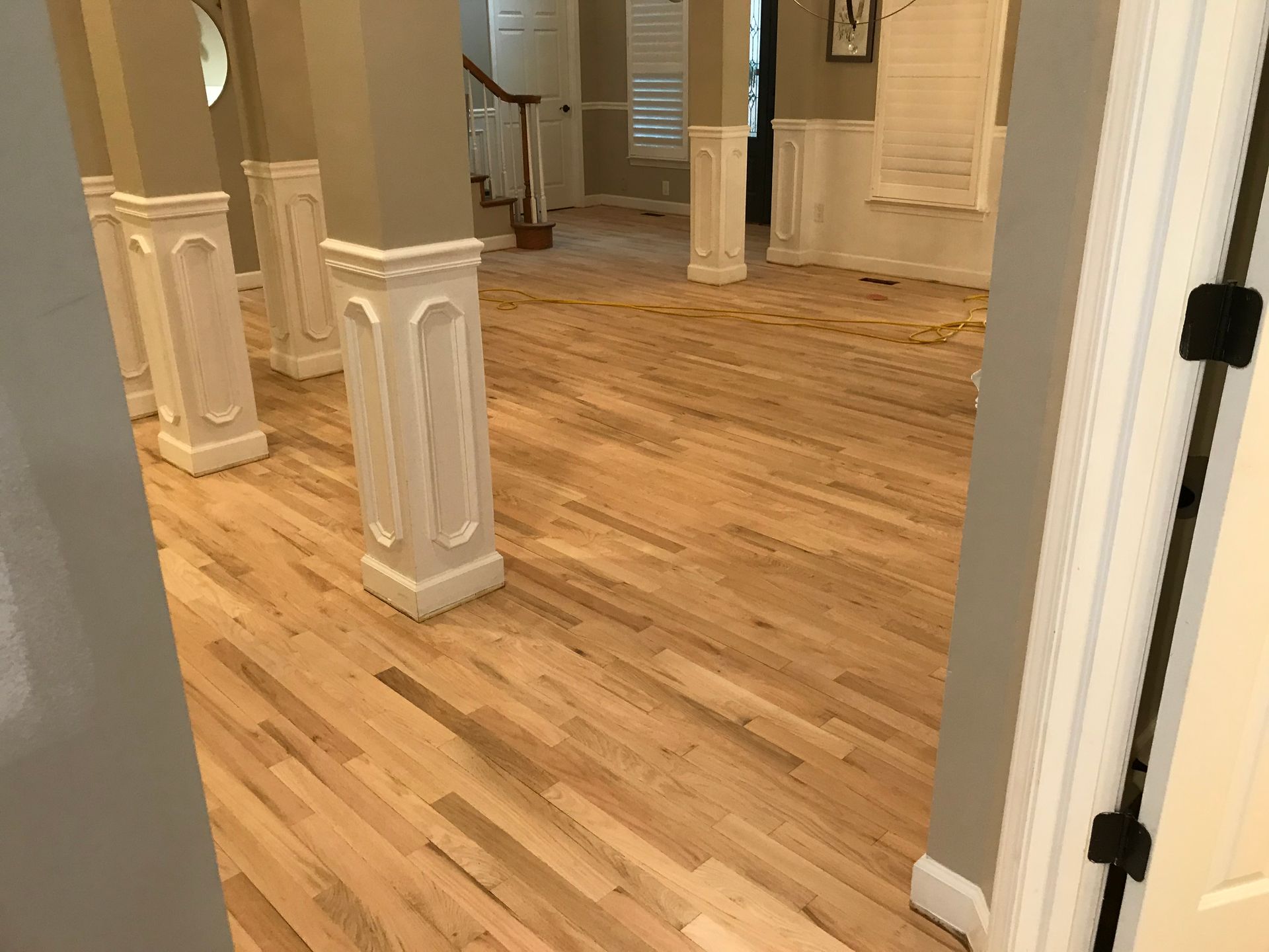 A hallway with hardwood floors and white columns in a house.