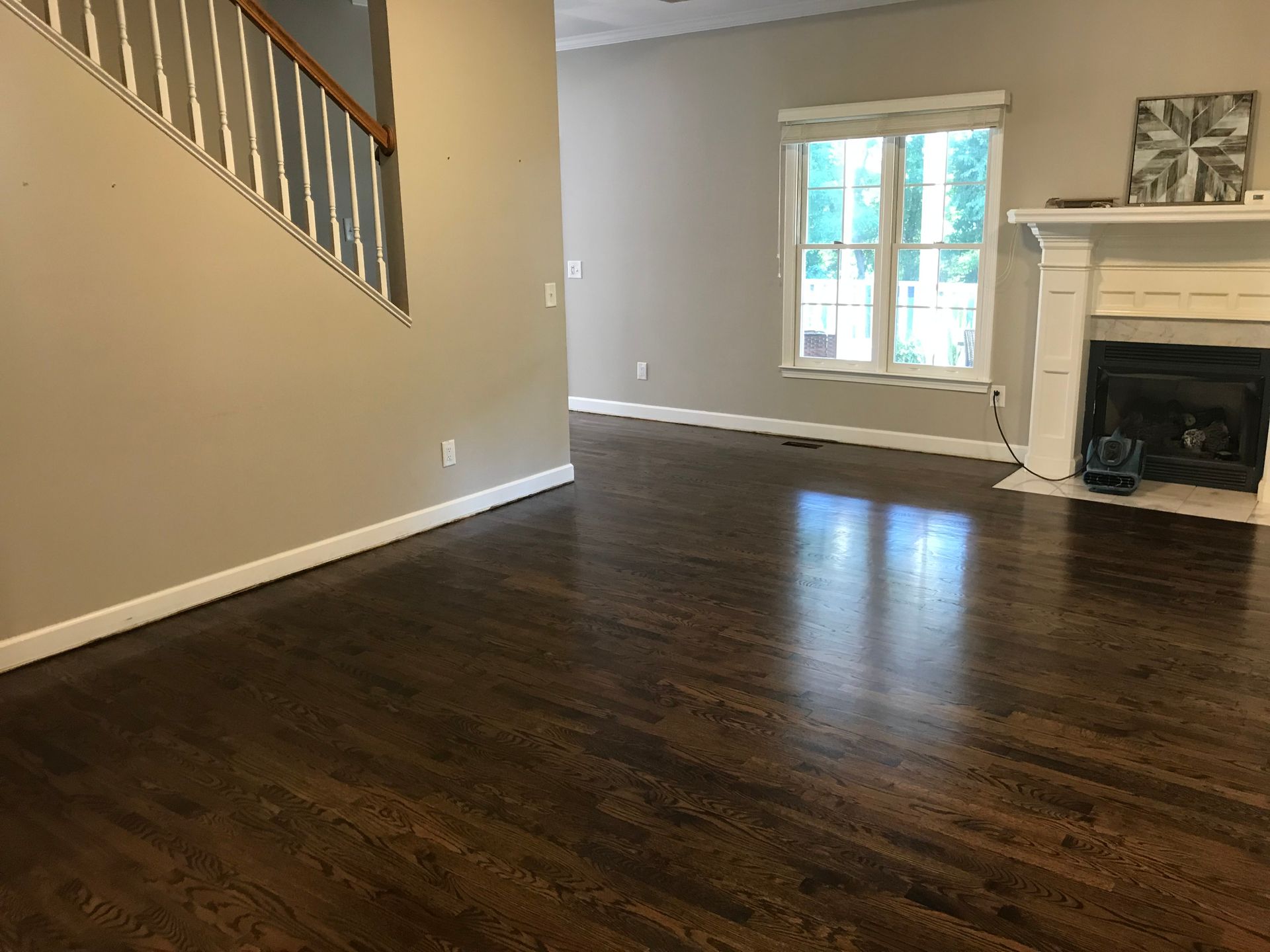 An empty living room with hardwood floors and a fireplace.