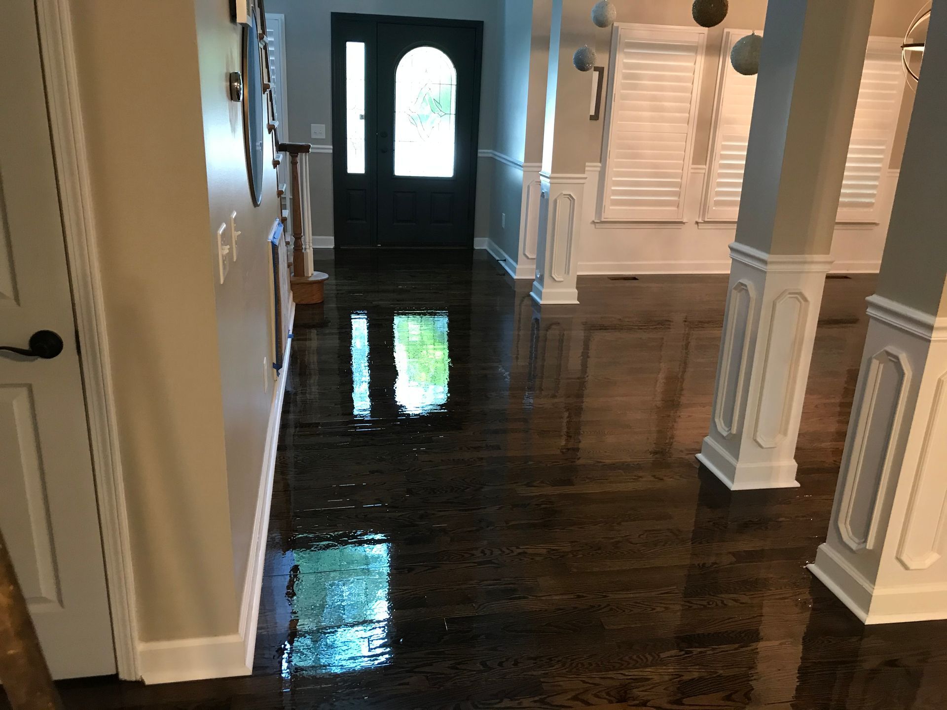 A hallway in a house with a hardwood floor and a door.
