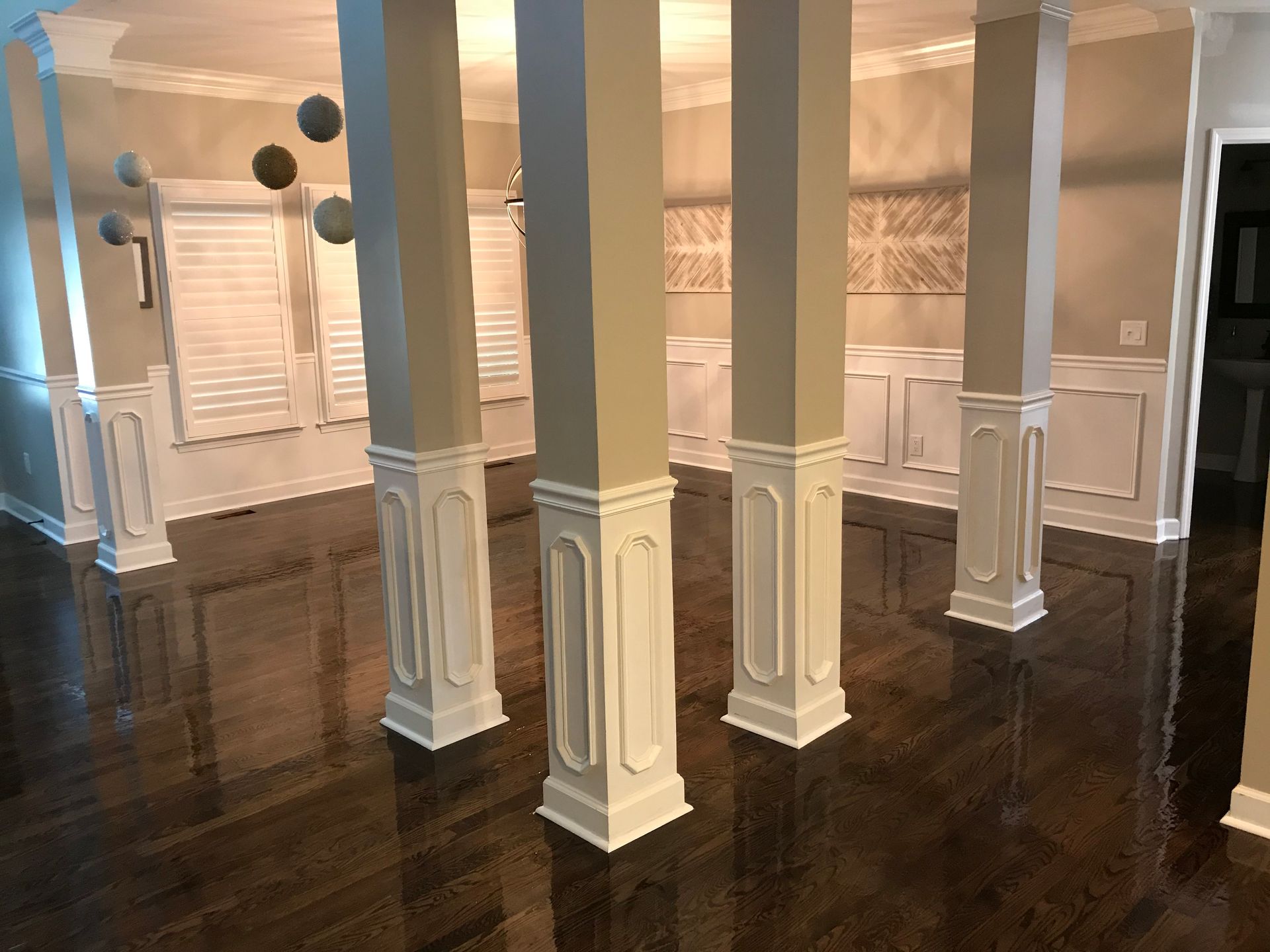 A living room with columns and a hardwood floor.