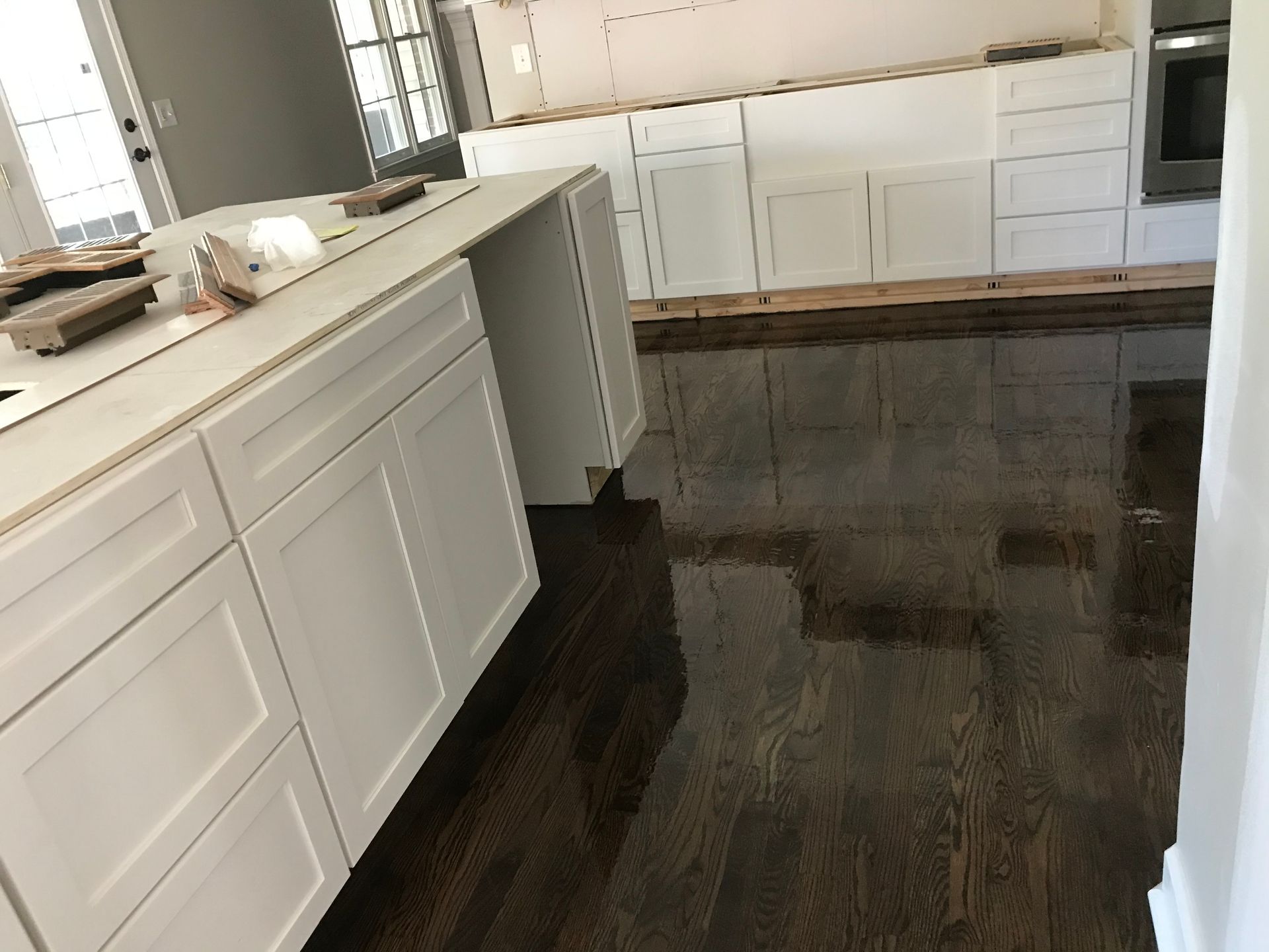 A kitchen with white cabinets and a dark wood floor
