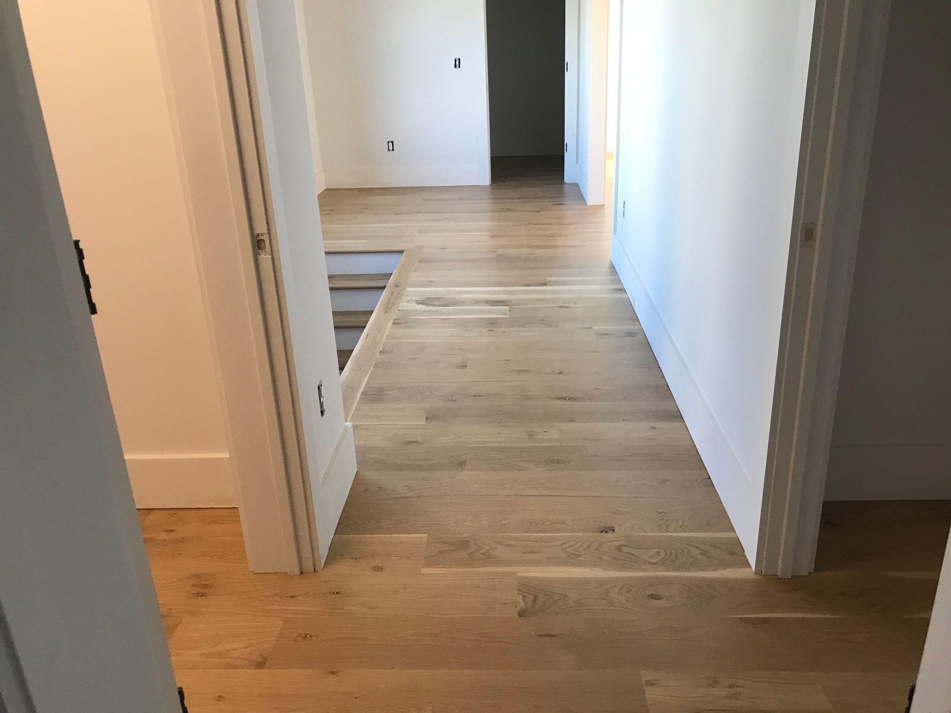 A hallway with hardwood floors and white walls