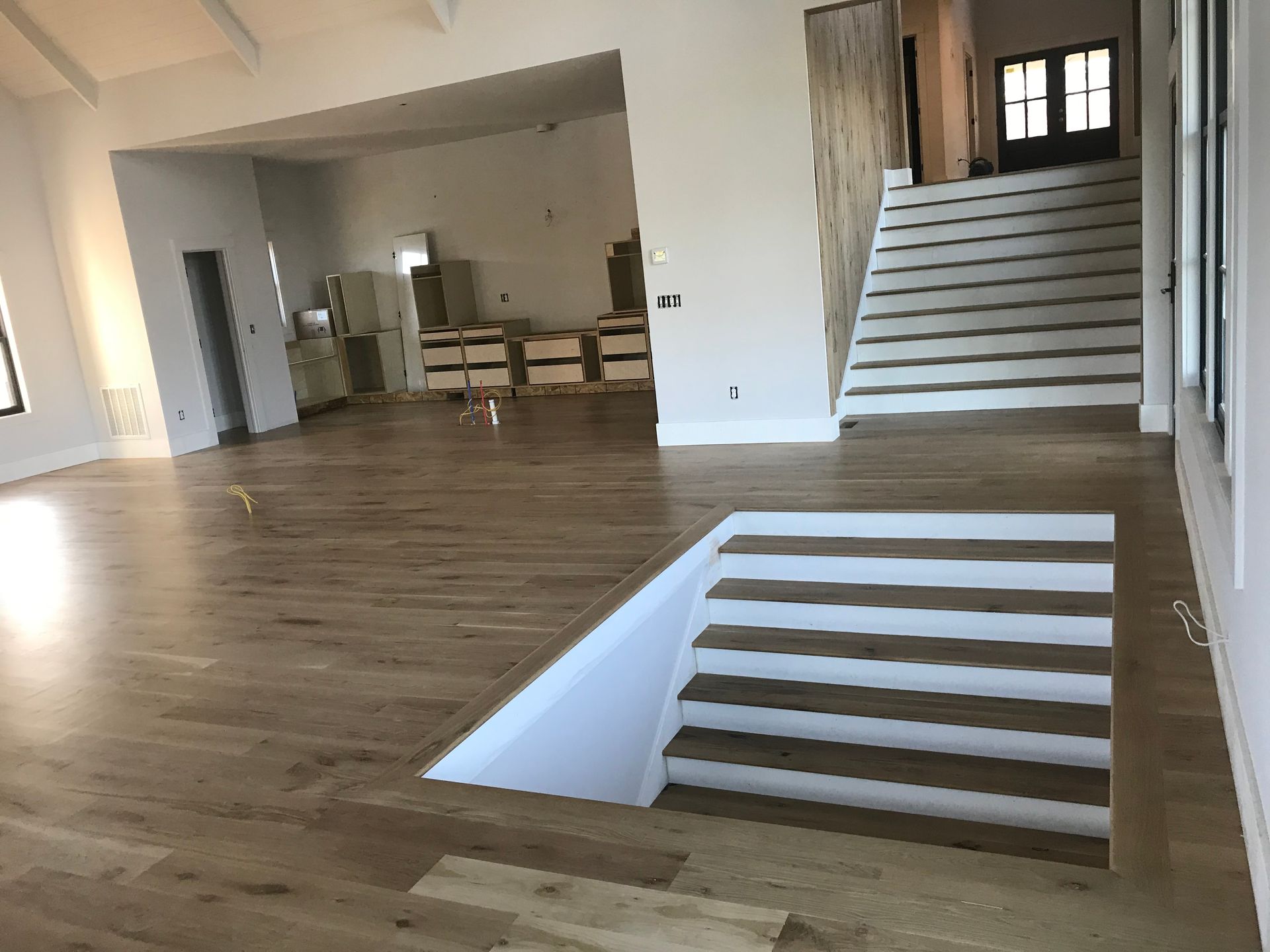 A large empty room with wooden floors and stairs.
