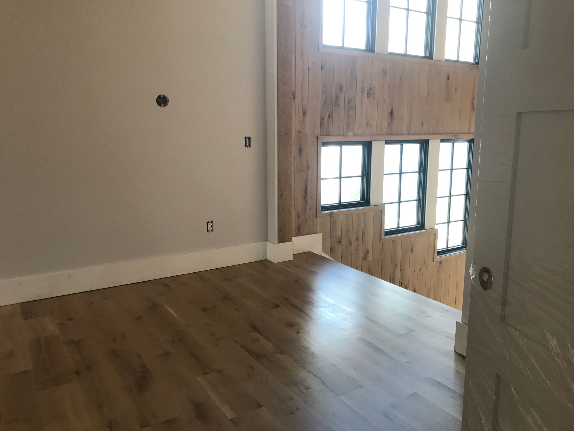 An empty room with hardwood floors and lots of windows