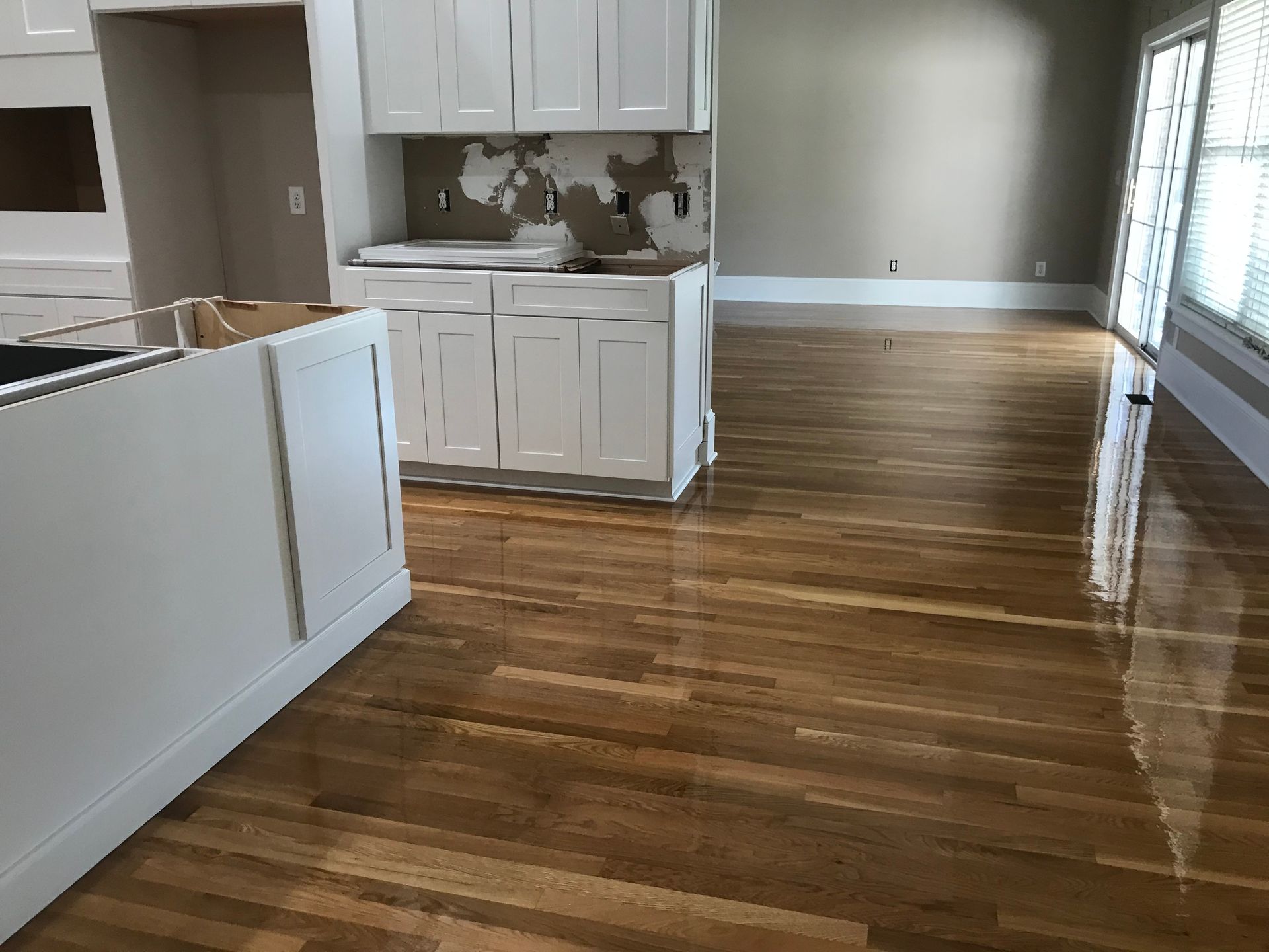 A kitchen with hardwood floors and white cabinets is being remodeled.