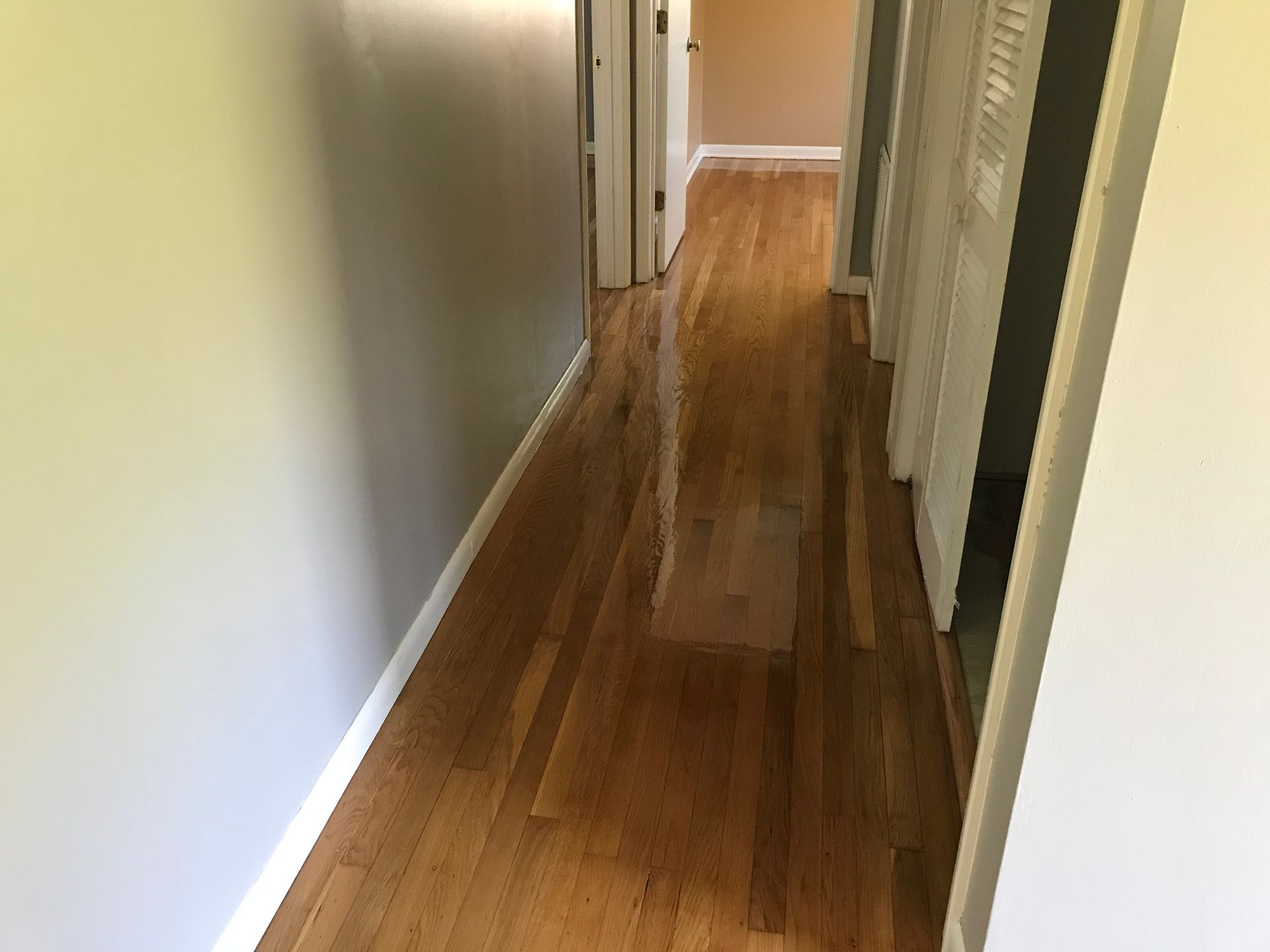 A long hallway with hardwood floors and white walls