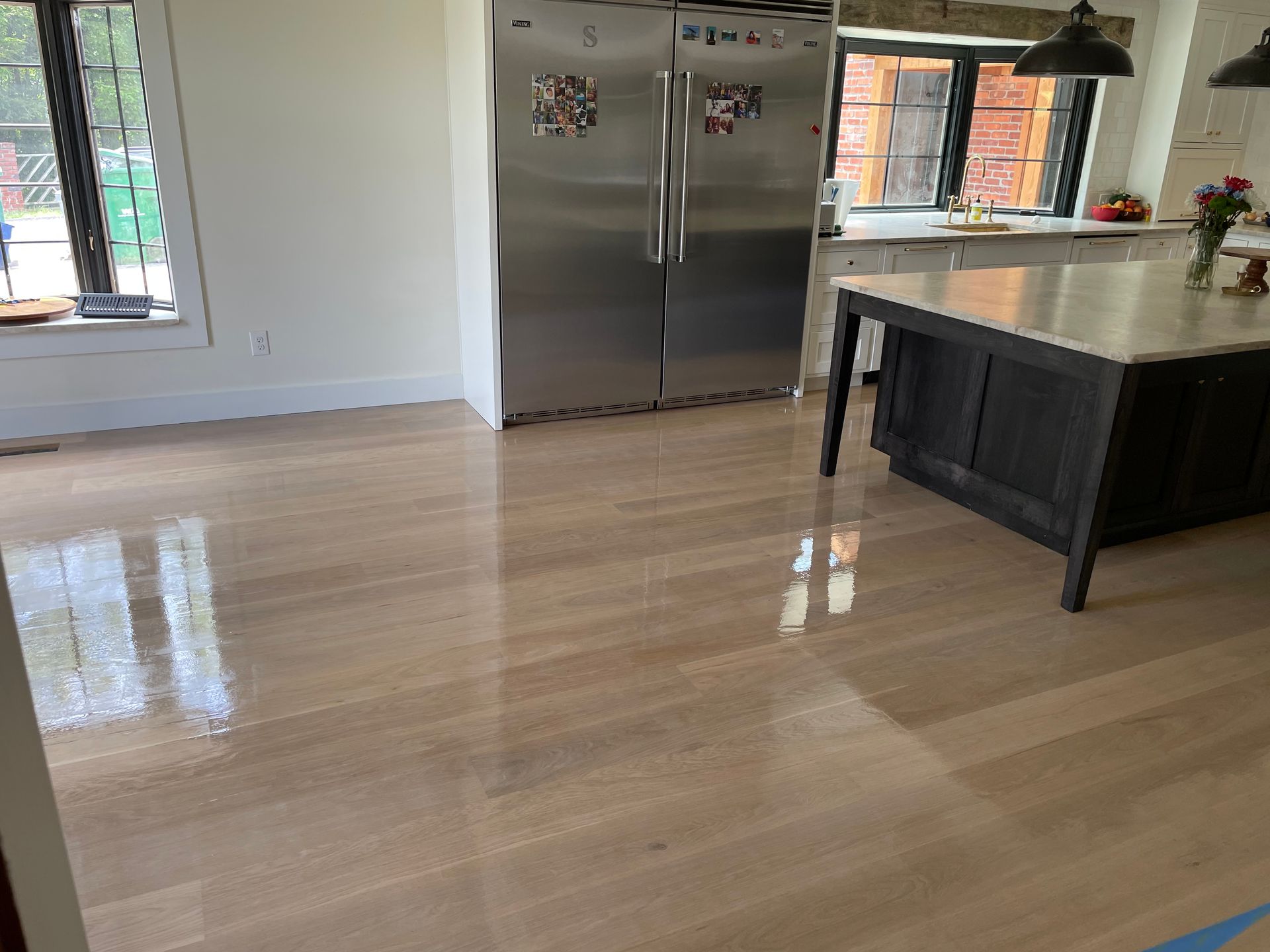 A kitchen with a stainless steel refrigerator and a wooden floor.