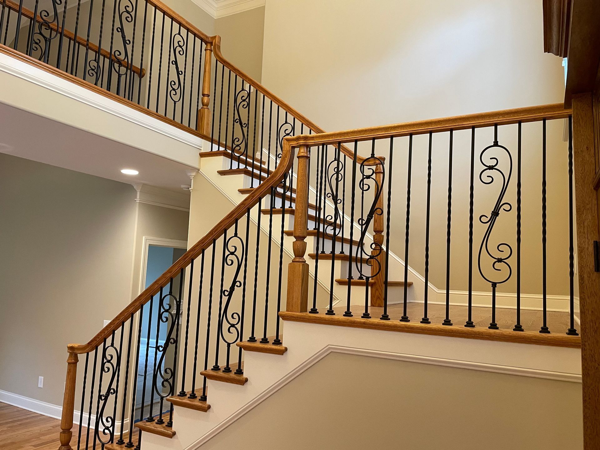 A wooden staircase with a wrought iron railing in a house.