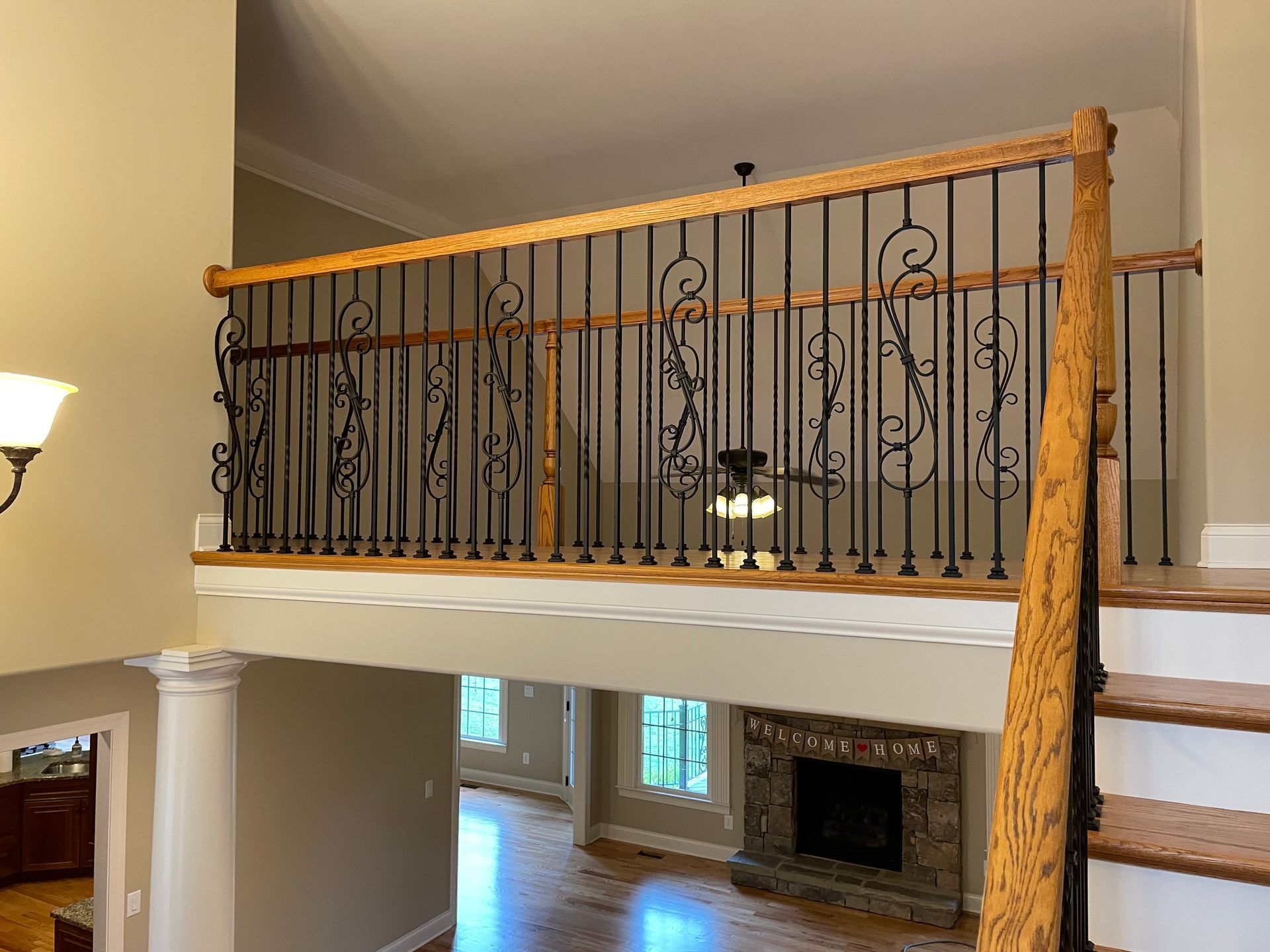 A living room with stairs leading up to a balcony and a fireplace.