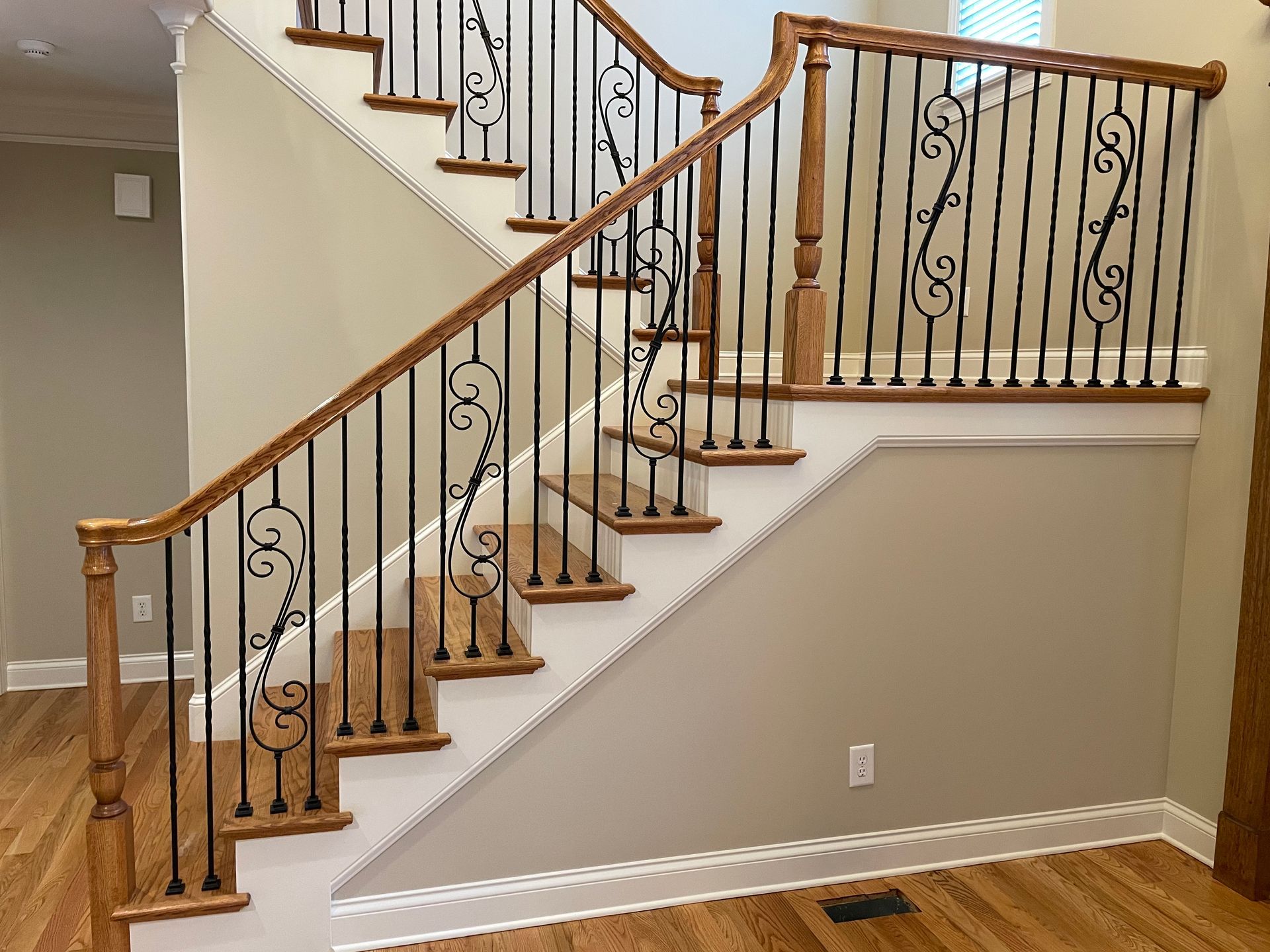 A wooden staircase with a wrought iron railing in a house.