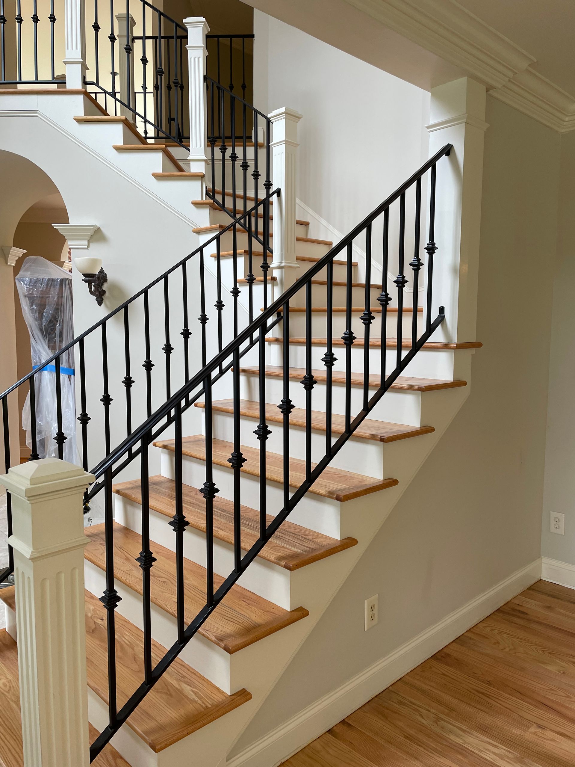 A staircase with a wrought iron railing and wooden steps