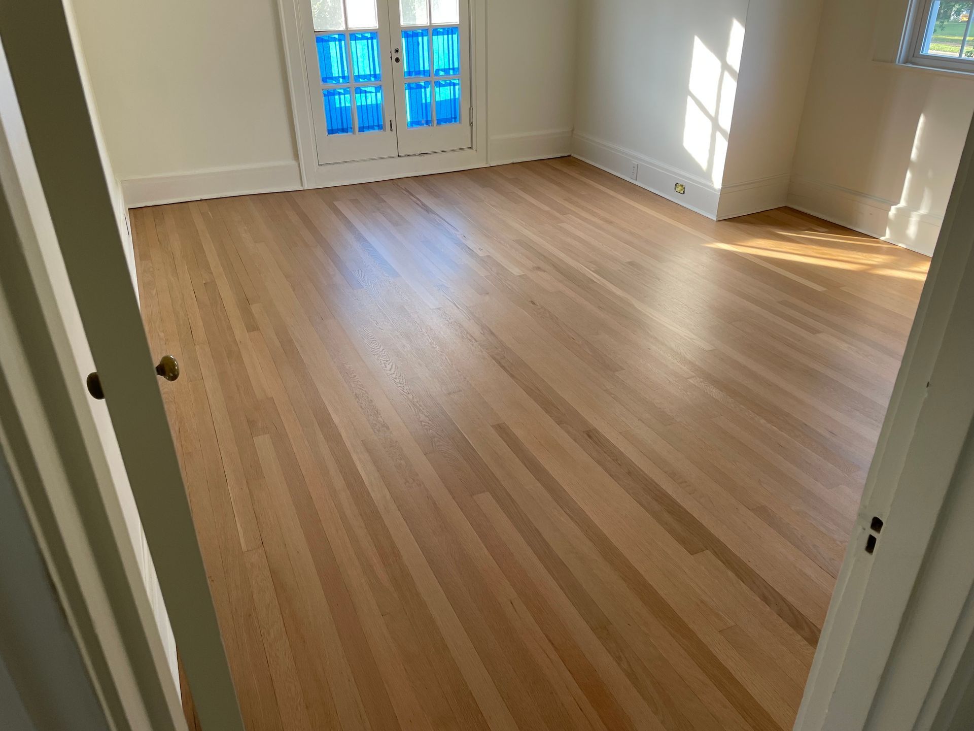 An empty room with hardwood floors and french doors.