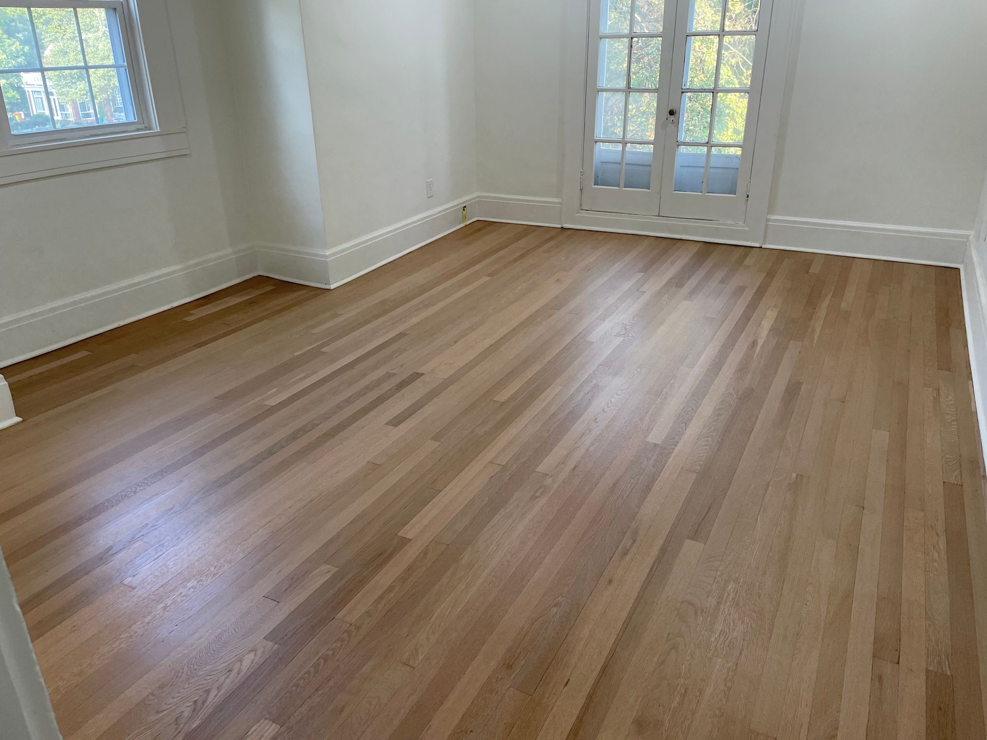 An empty room with hardwood floors and white walls.