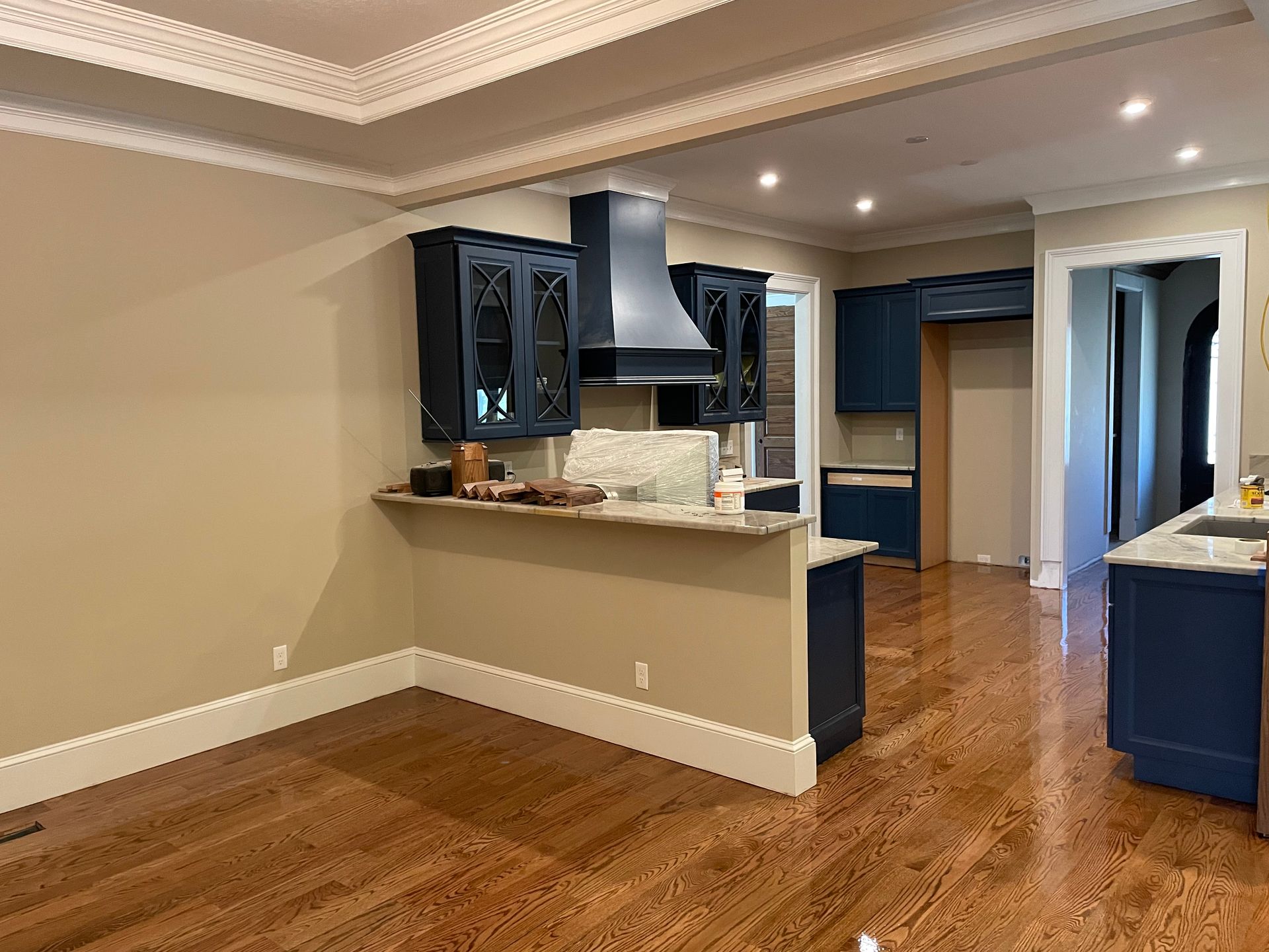 An empty kitchen with blue cabinets and hardwood floors.