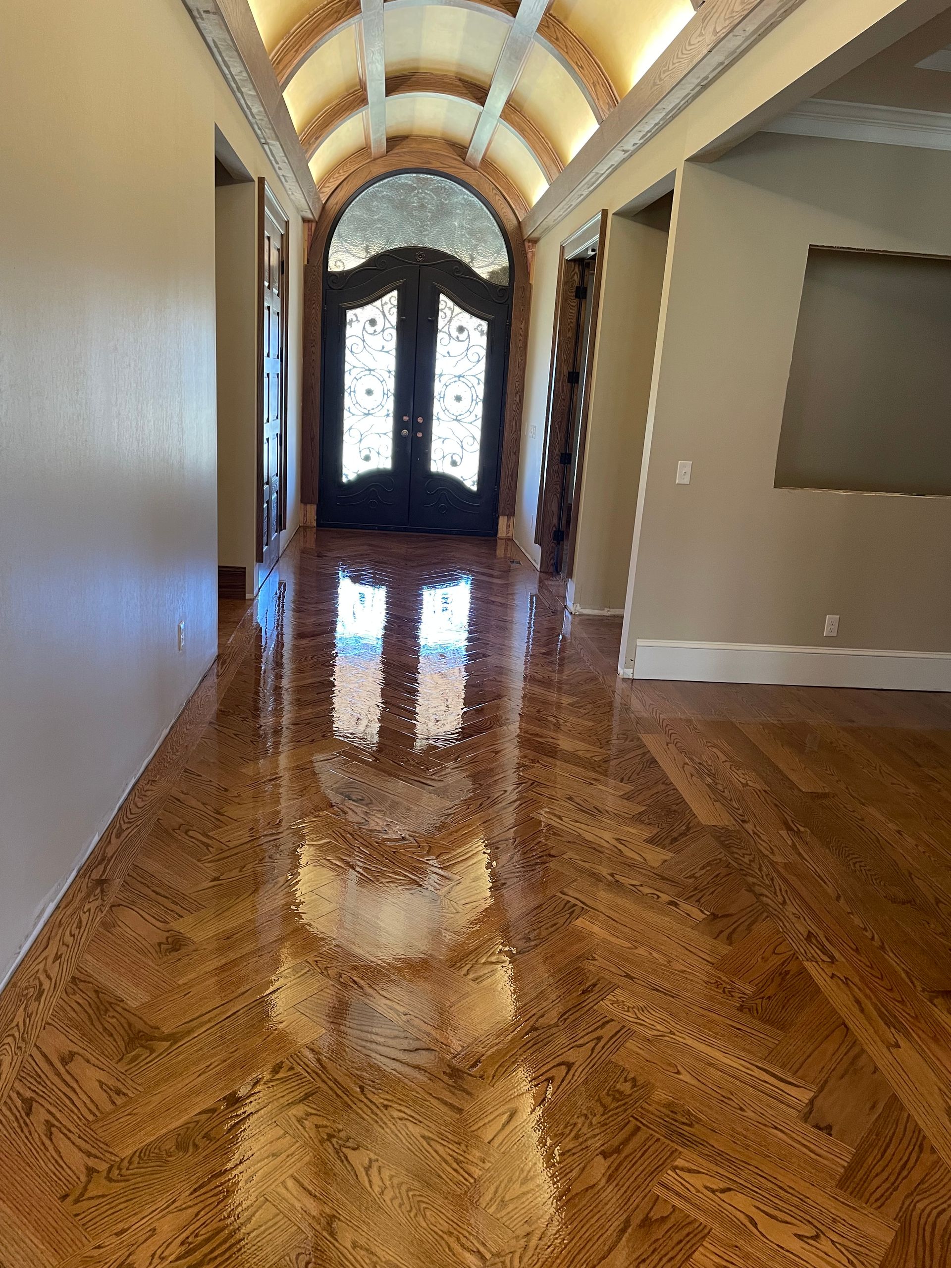 A hallway with a wooden floor and a door in a house.