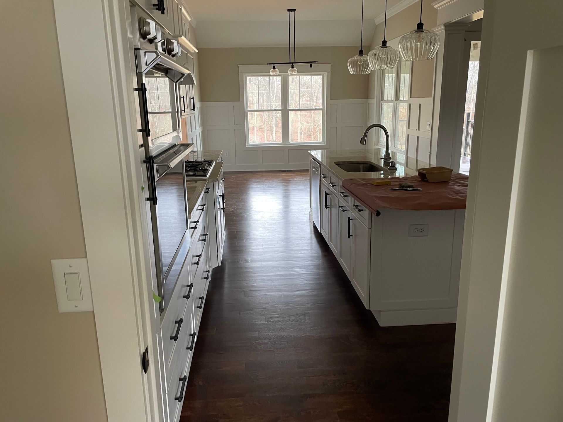 A kitchen with white cabinets , stainless steel appliances , and hardwood floors.