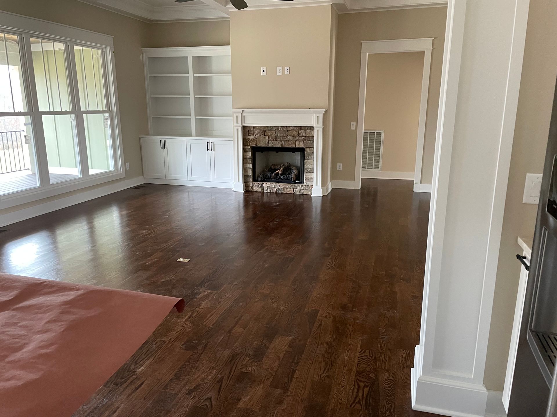 An empty living room with hardwood floors and a fireplace.