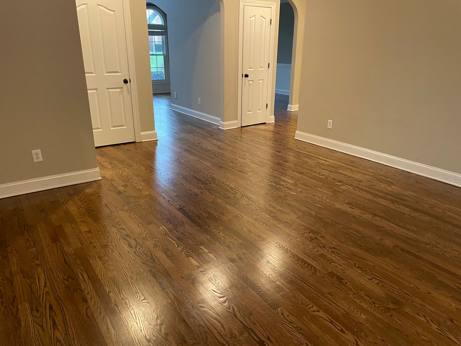 An empty living room with hardwood floors and white trim.