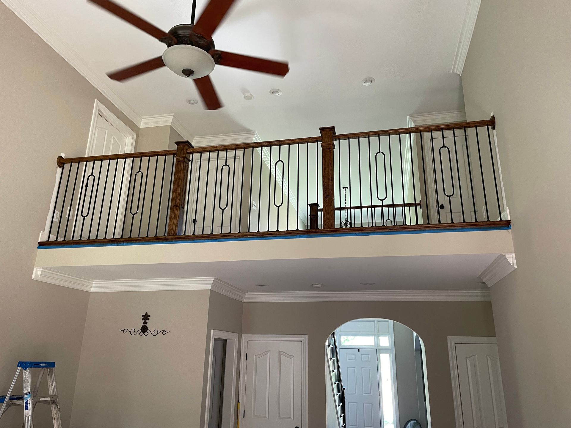 A living room with a balcony and a ceiling fan.