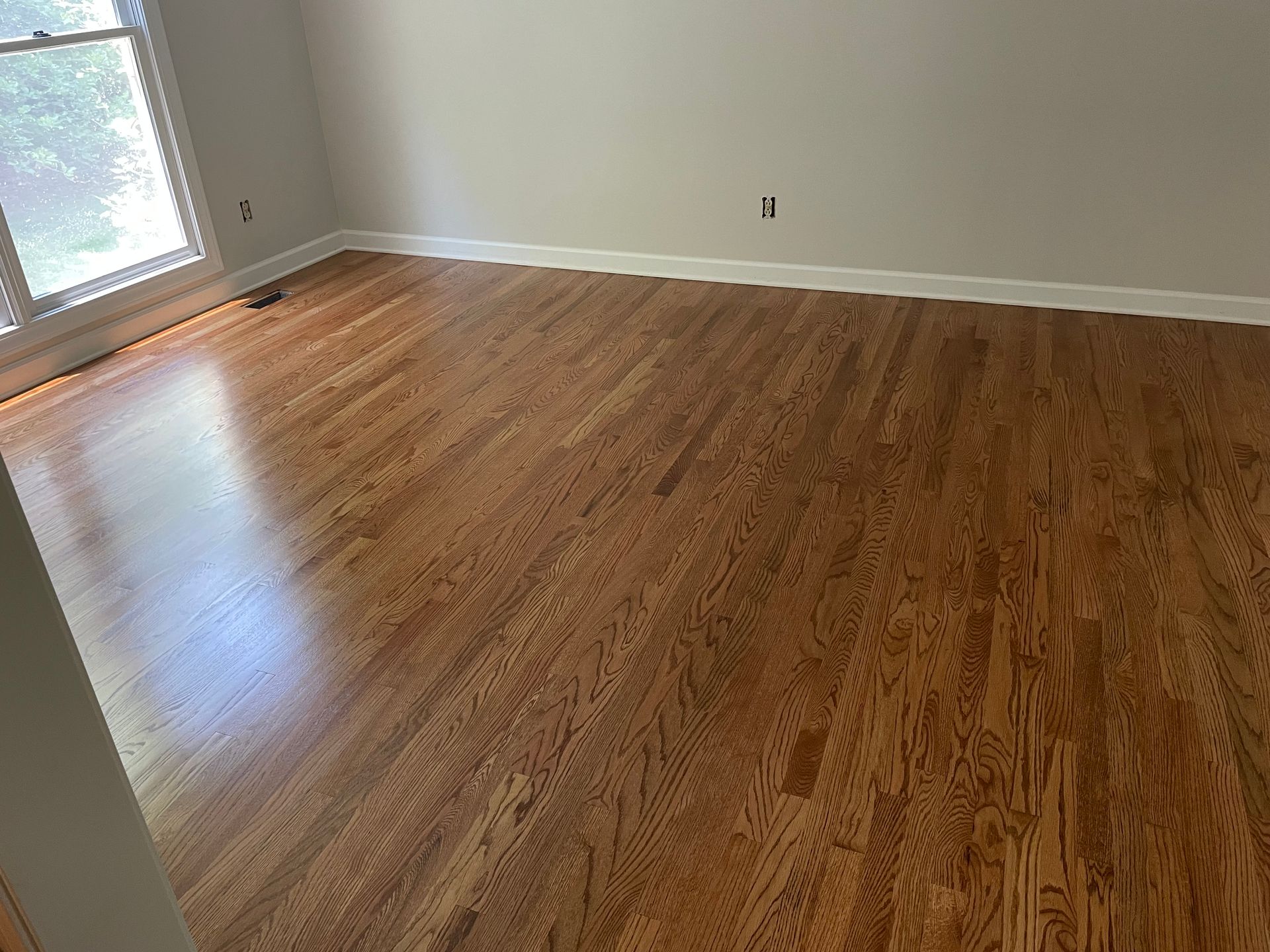 A living room with hardwood floors and a window.