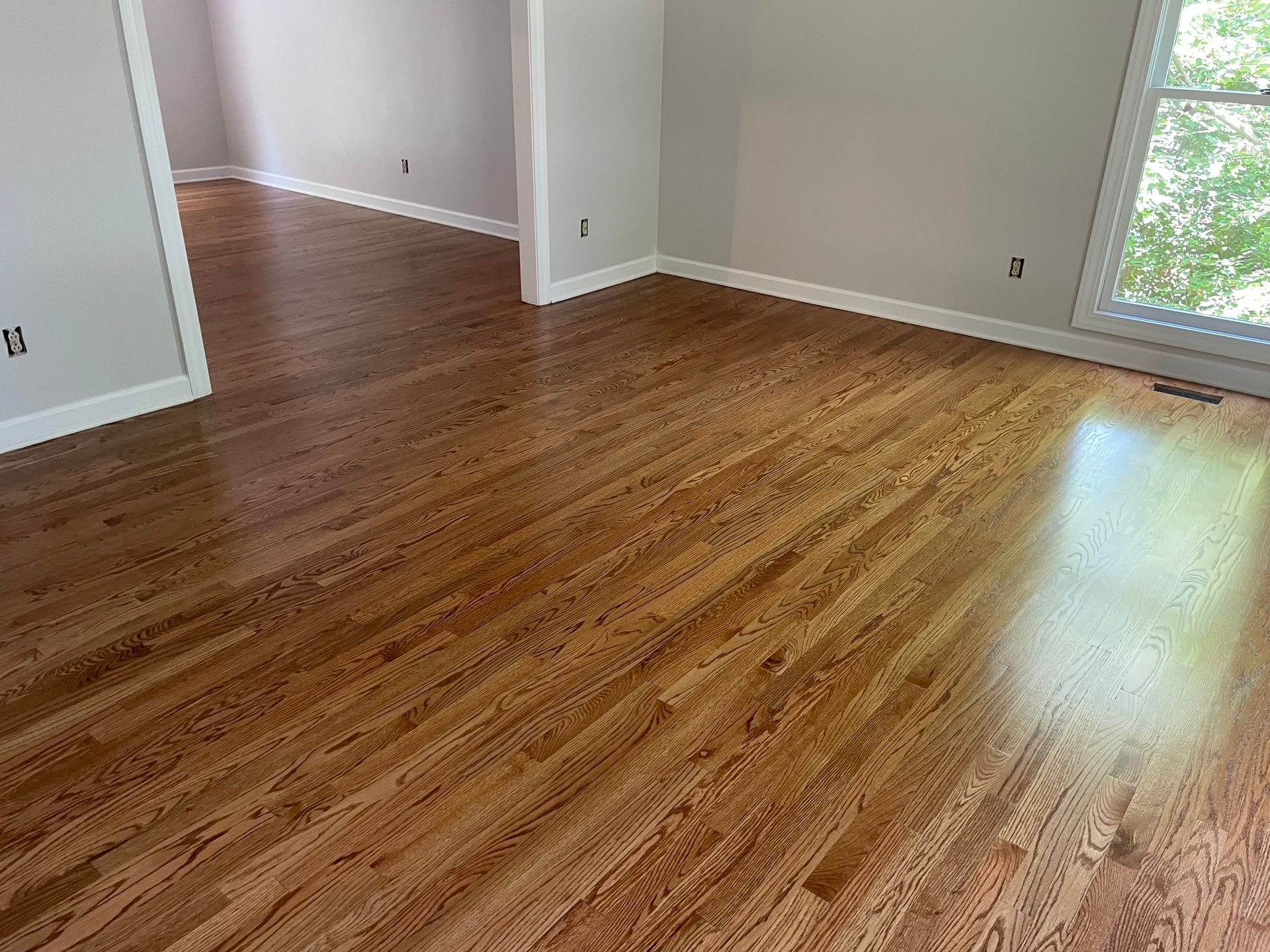 A living room with hardwood floors and a window.