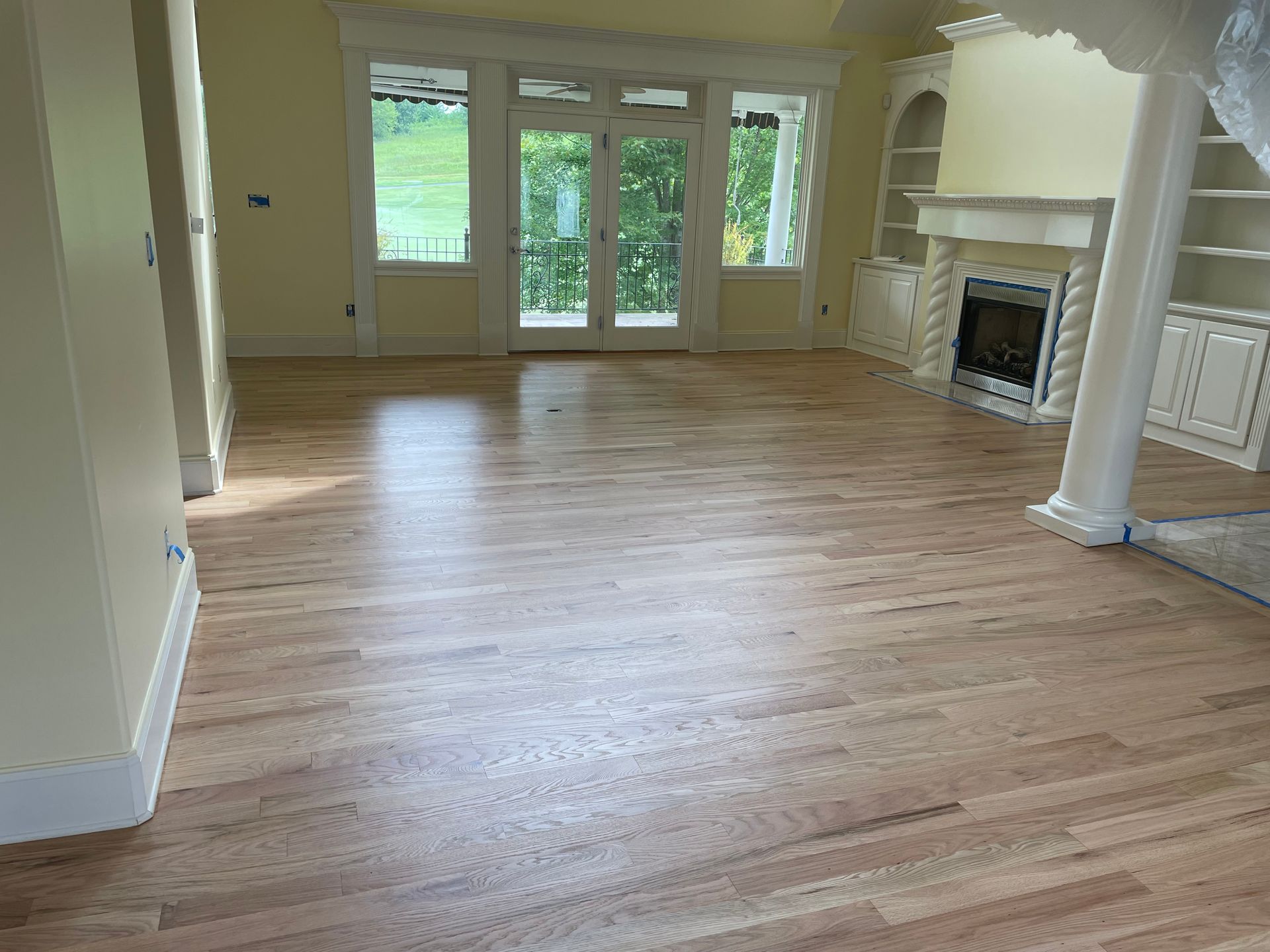 An empty living room with hardwood floors and a fireplace.