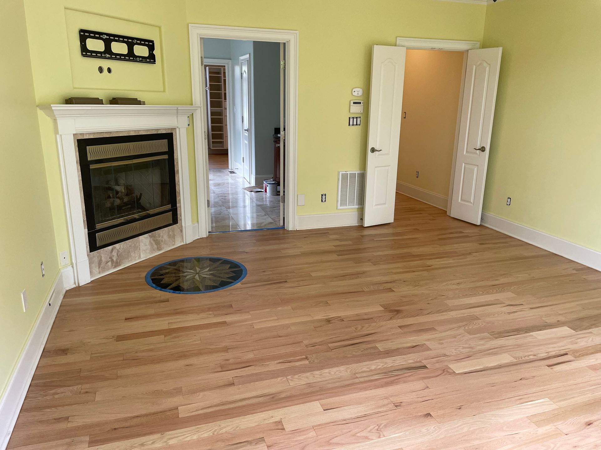 An empty living room with hardwood floors and a fireplace.