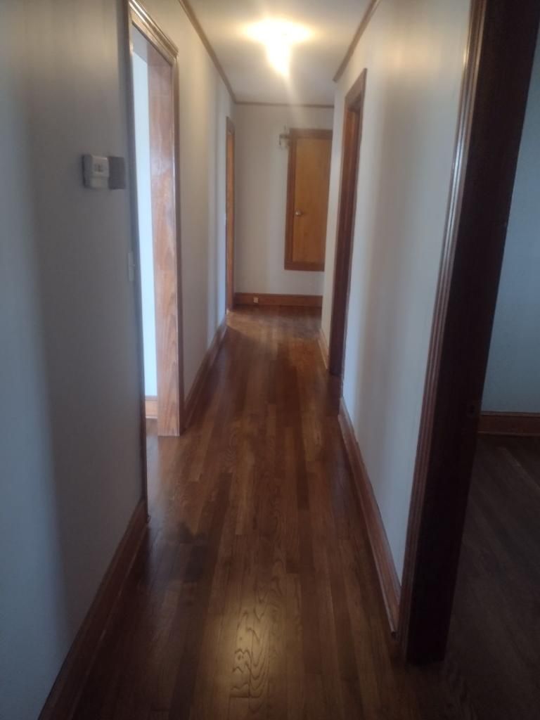 A long hallway with wooden floors and white walls