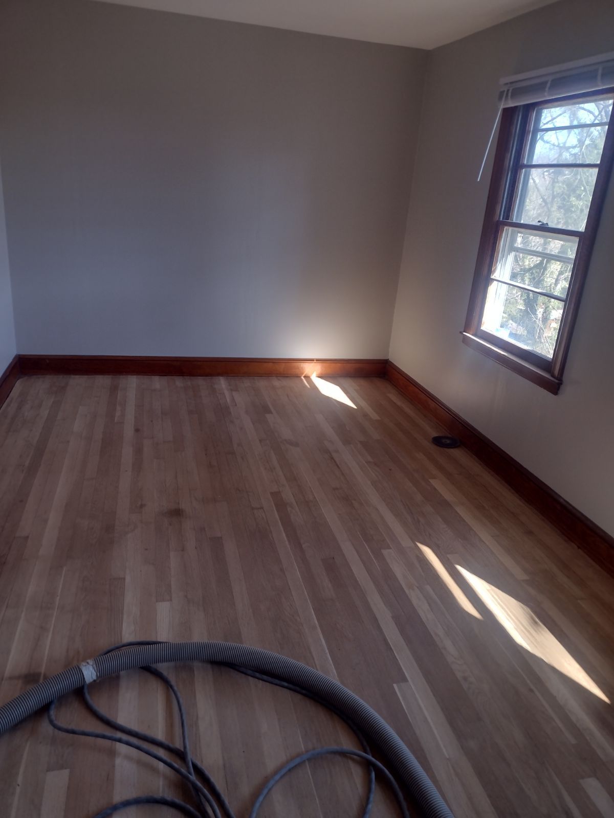 An empty room with hardwood floors and a window
