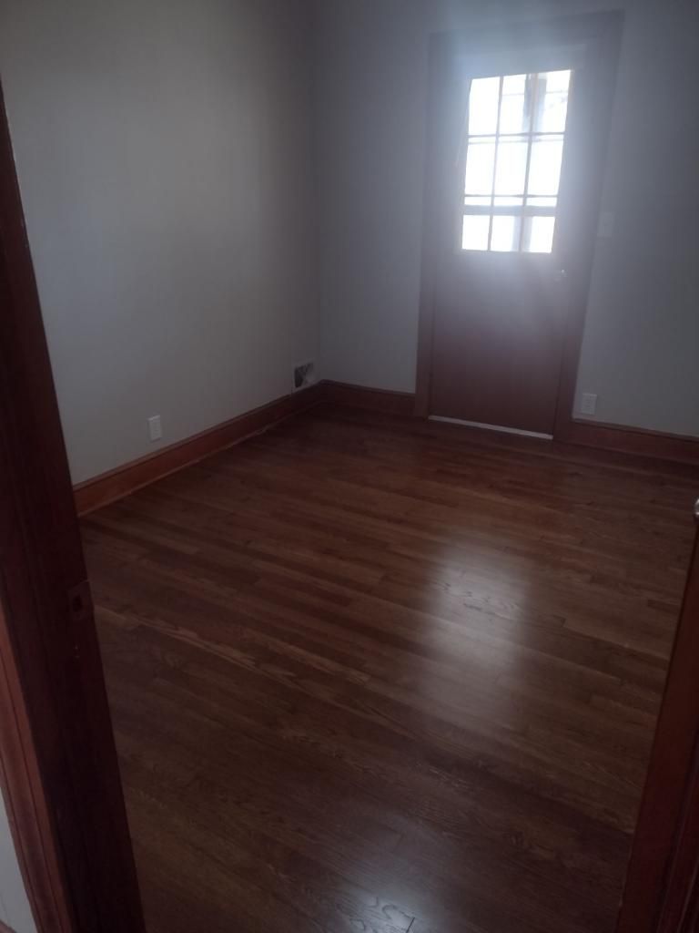 An empty room with hardwood floors and a door.