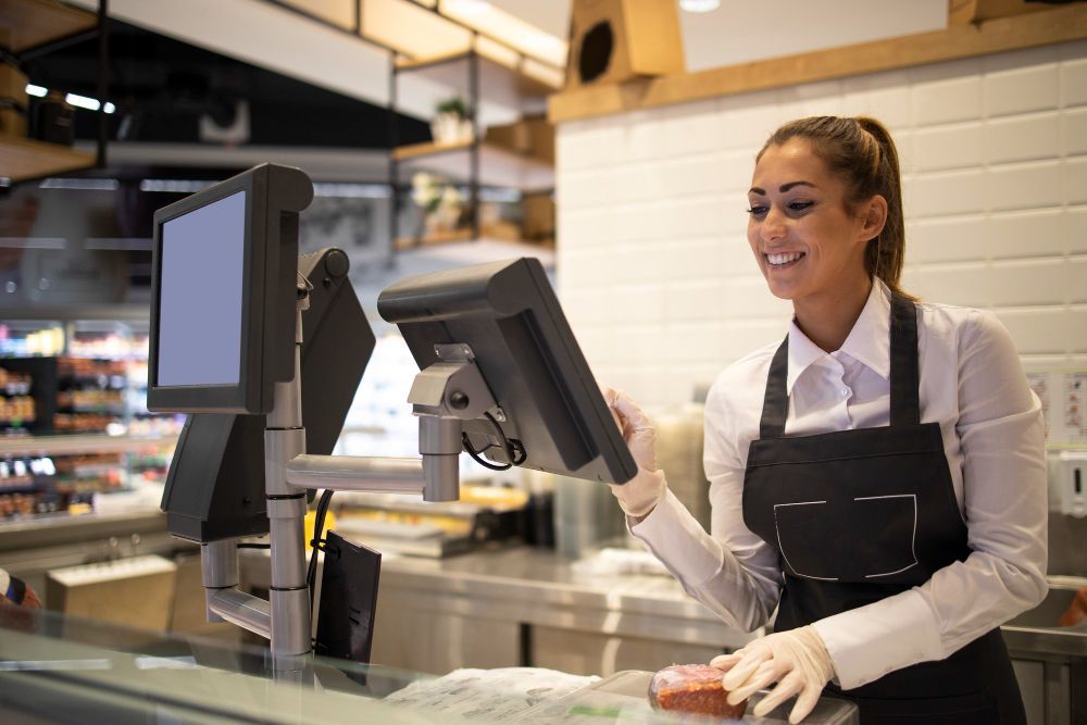 Una mujer está parada frente a una computadora en un restaurante.