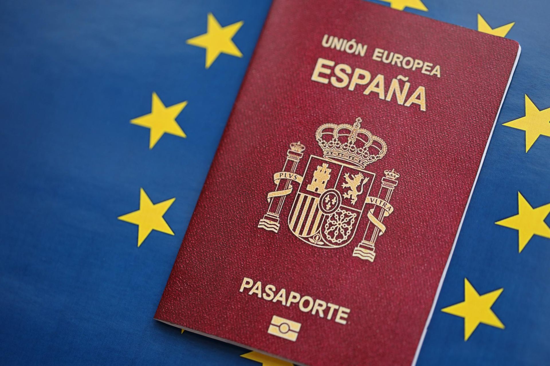 Un pasaporte español está sobre un fondo azul con estrellas amarillas.